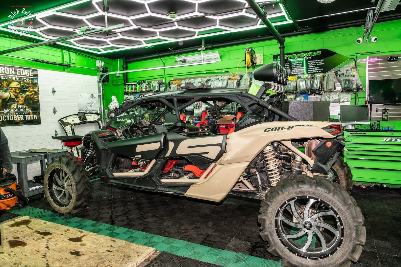 Custom off-road side-by-side in a neon green garage with a lifted suspension and large tires. | East End Auto Kicks