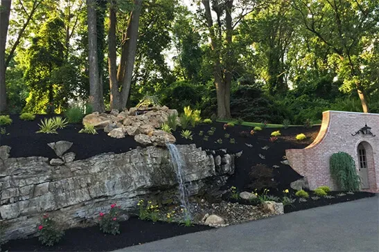 Tiered backyard waterfall with rocks and landscaping design.