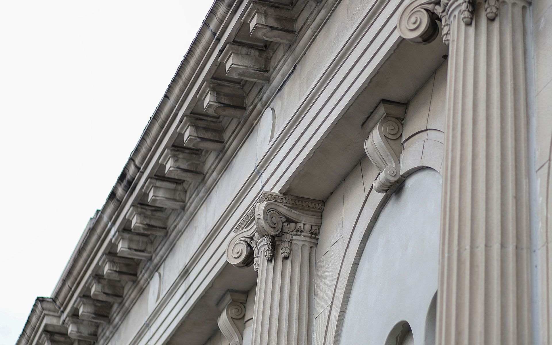 Close-up of a building's classical architectural details: fluted columns, ornate capitals, and decorative molding.