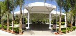 Una gran carpa blanca está rodeada de árboles en un parque.