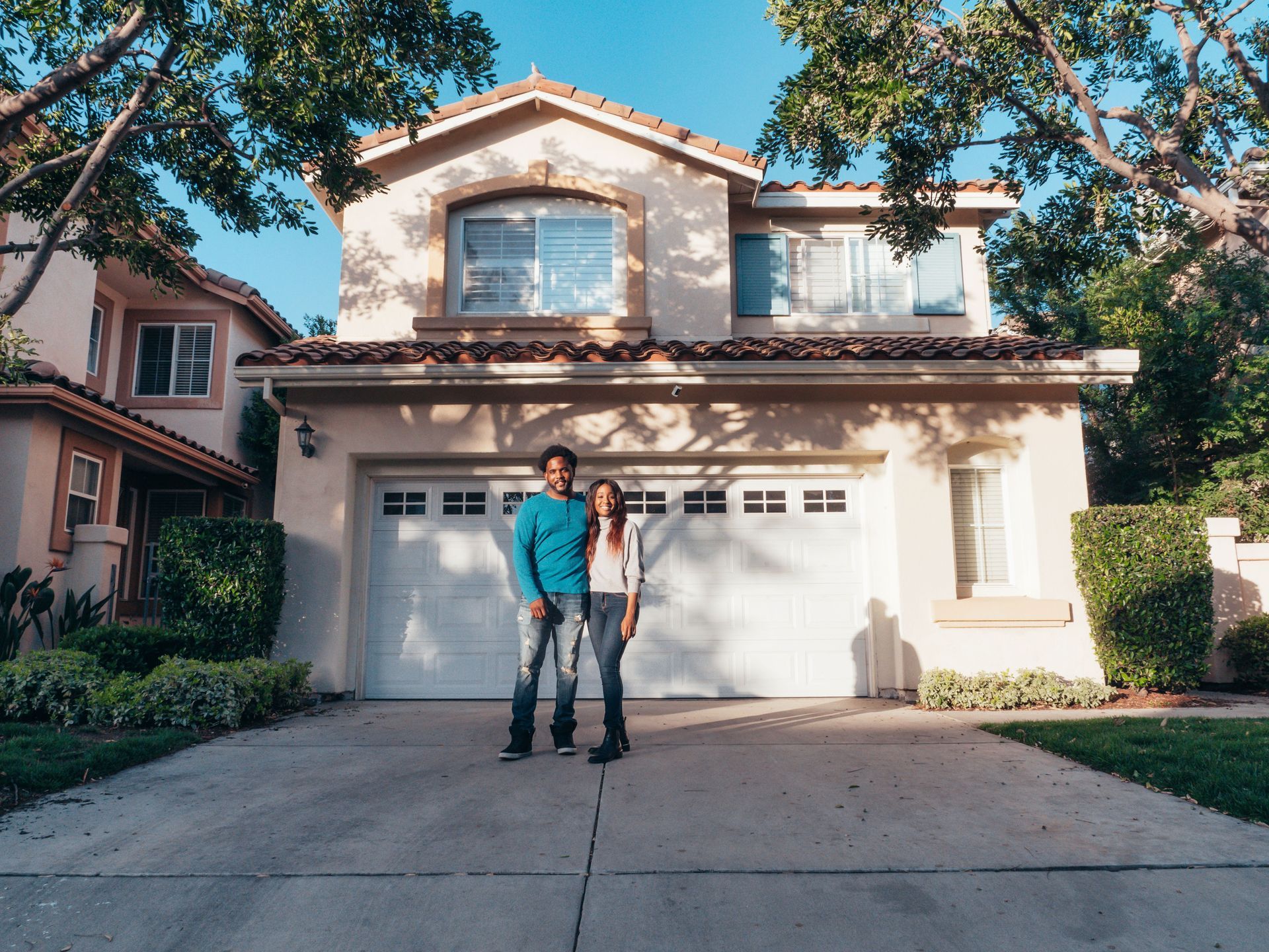 Two people standing in a driveway in front of a two-story house with a garage