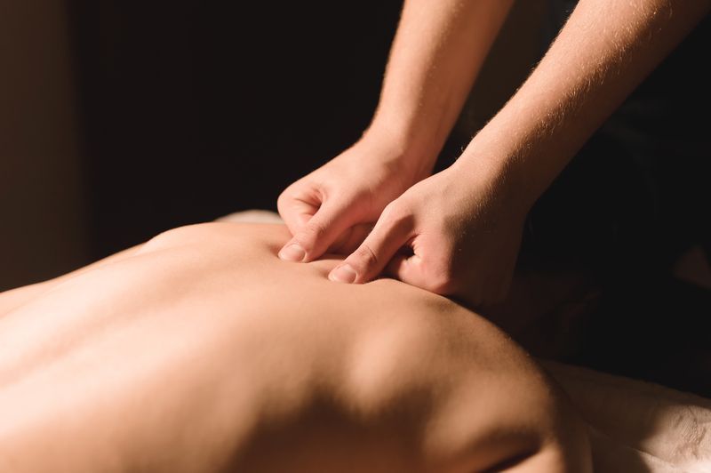 Hands massaging a person's back, close-up view.
