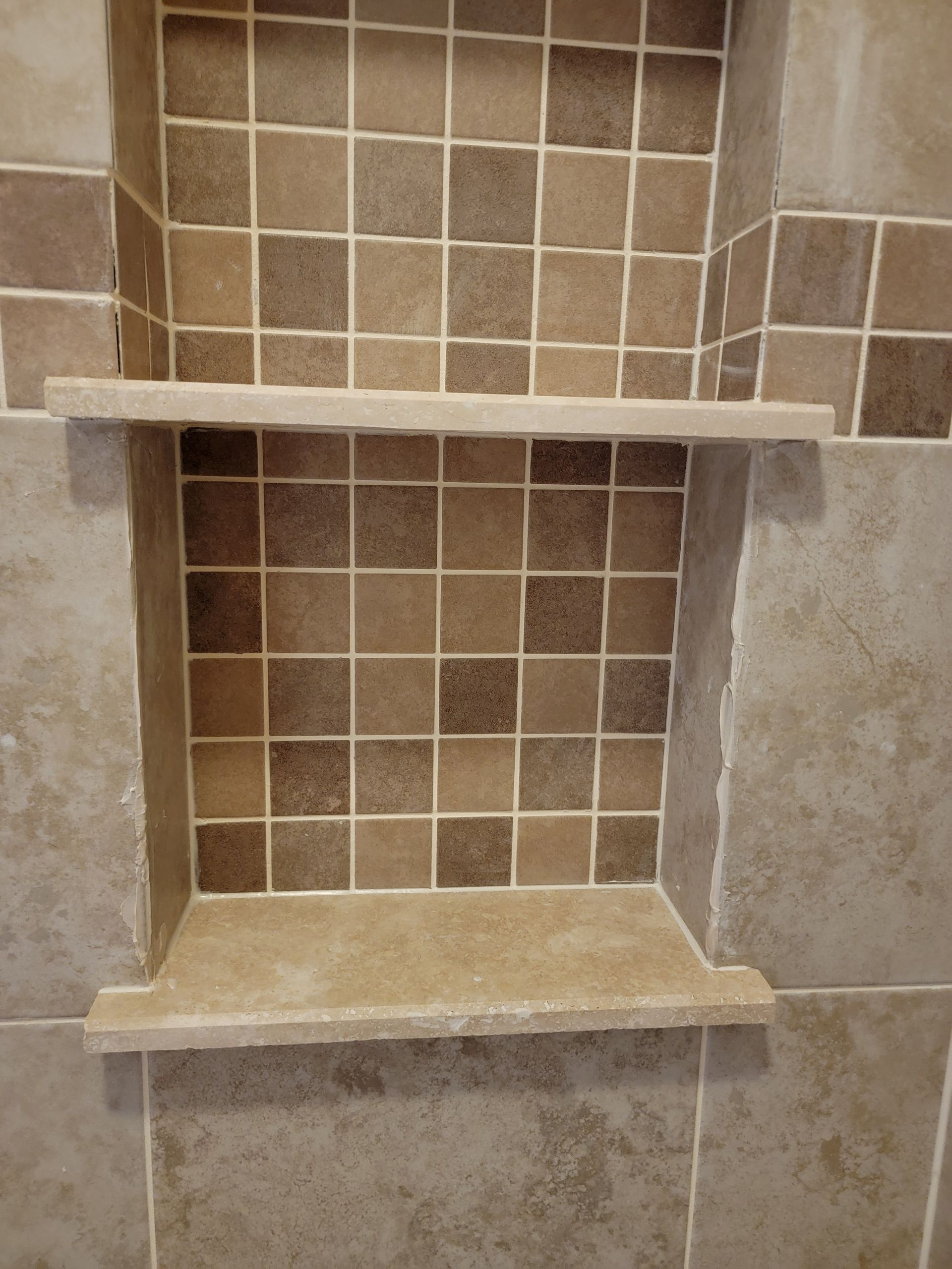 Bathroom shower niche with two shelves, tiled interior, beige and brown tones. Bathroom shower niche with two shelves, tiled interior, beige and brown tones.