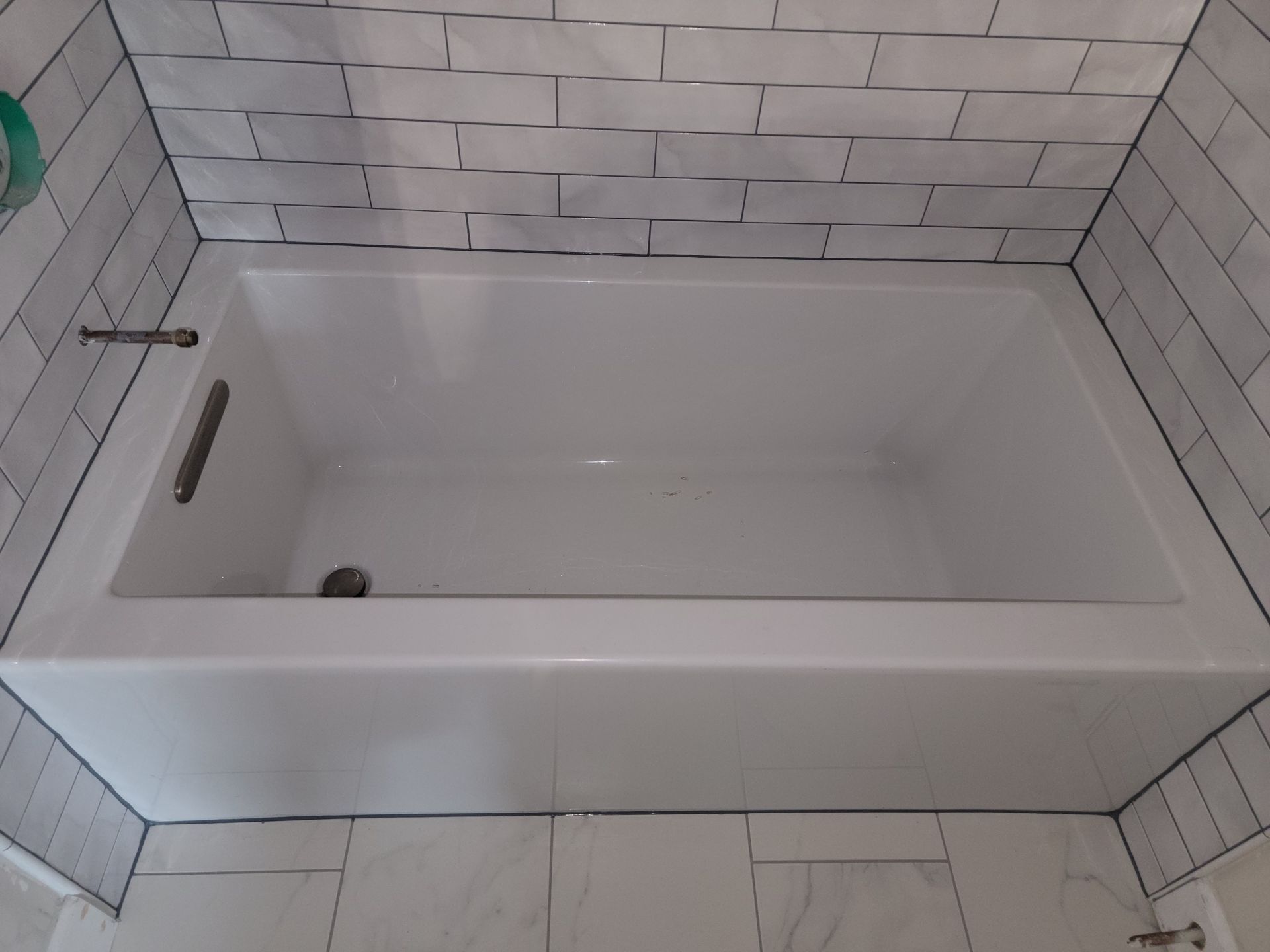 White bathtub with gray subway tile surround. White bathtub with gray subway tile surround.