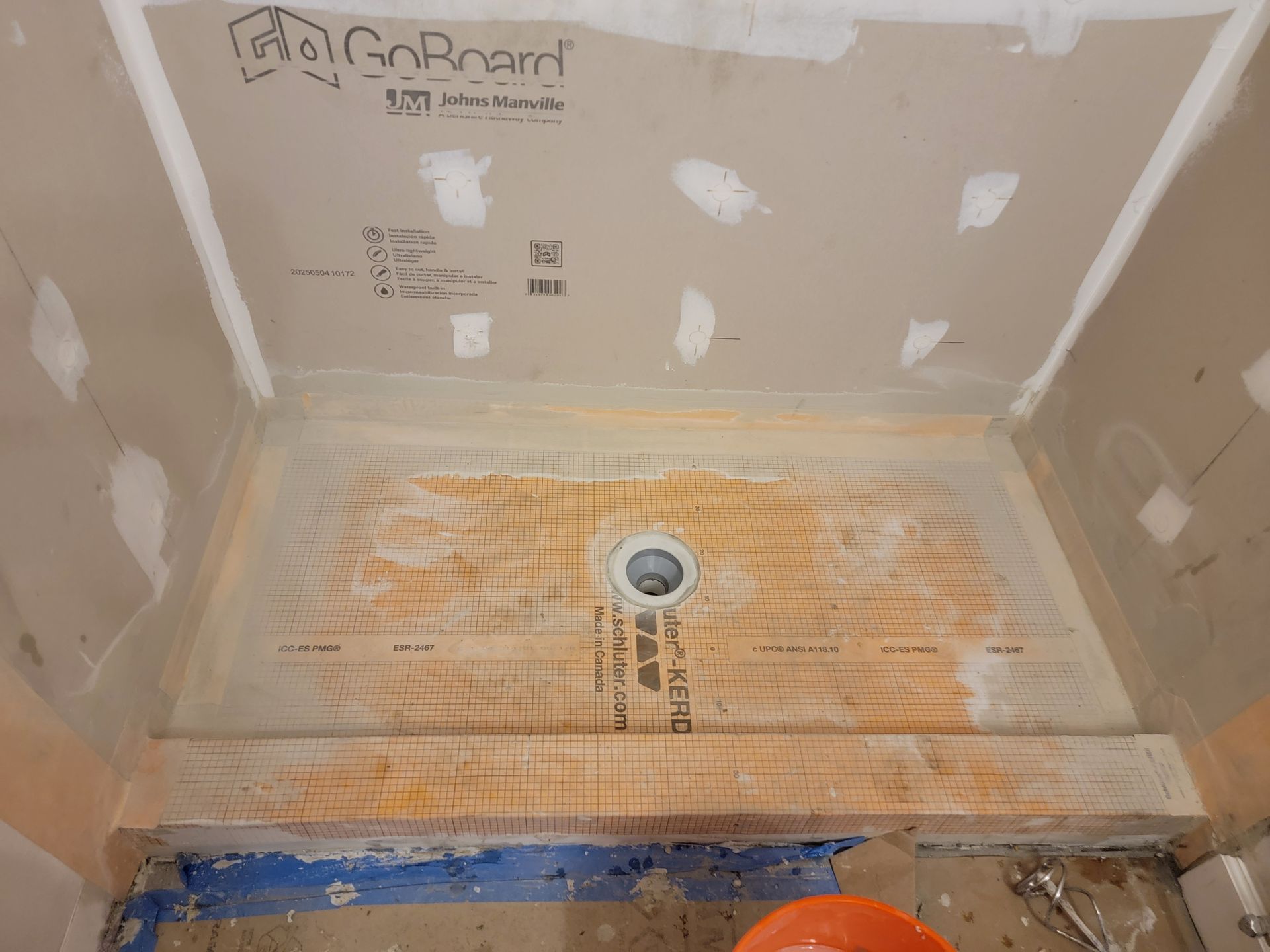 Shower stall with a pre-sloped floor and drain, ready for tile installation, set against drywall walls. Shower stall with a pre-sloped floor and drain, ready for tile installation, set against drywall walls.