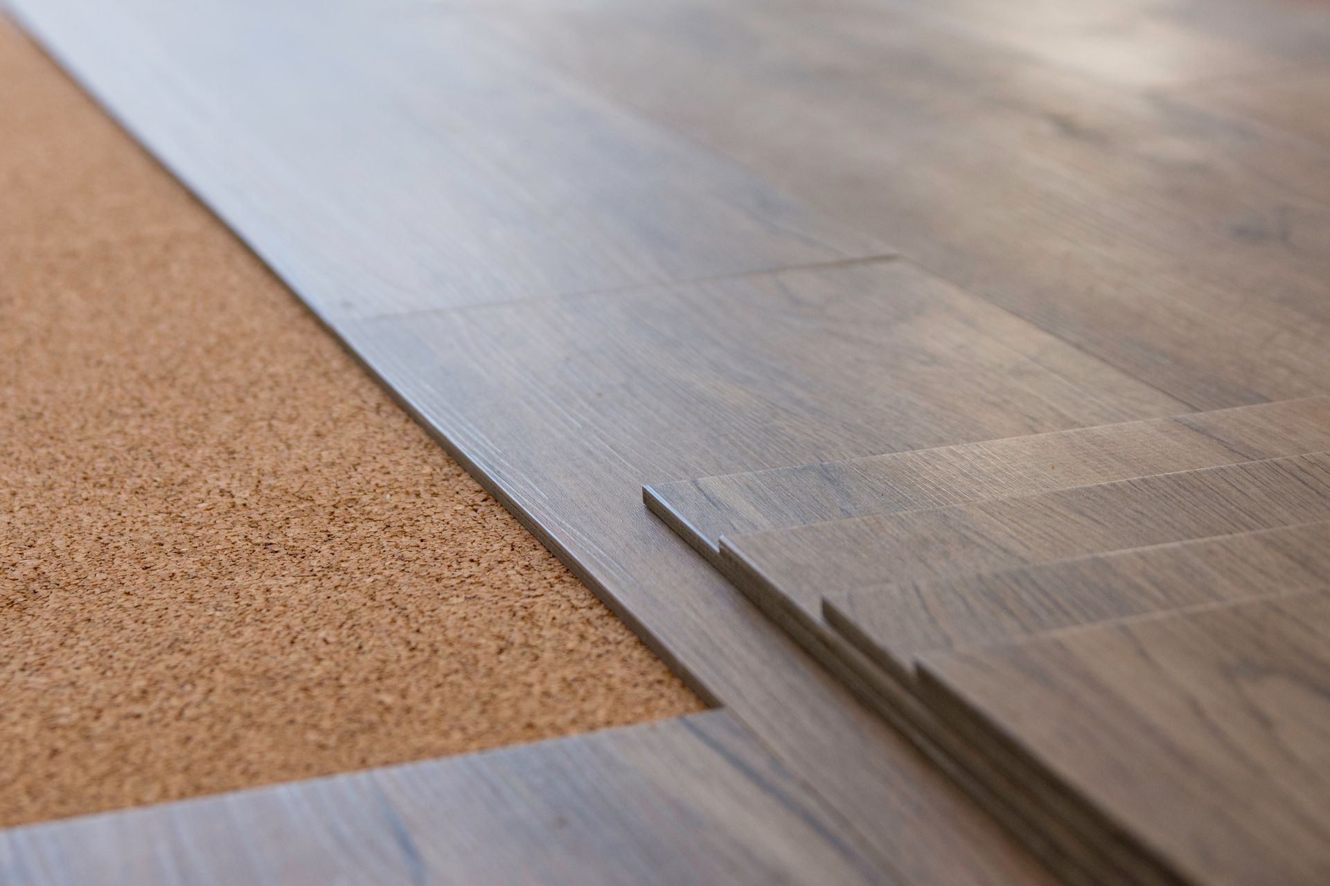Laminate flooring installation: planks being laid on top of brown cork underlayment. Laminate flooring installation: planks being laid on top of brown cork underlayment.