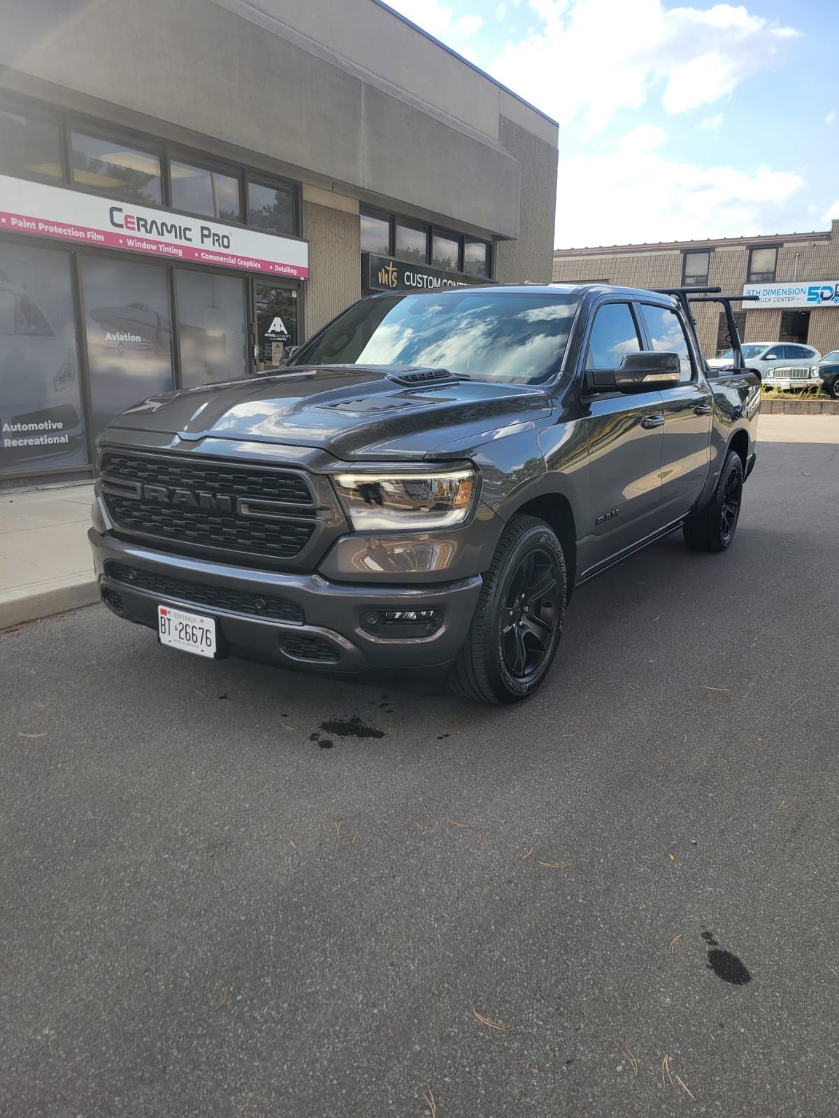 A dark gray Ram pickup truck parked in front of a commercial building with glass doors.