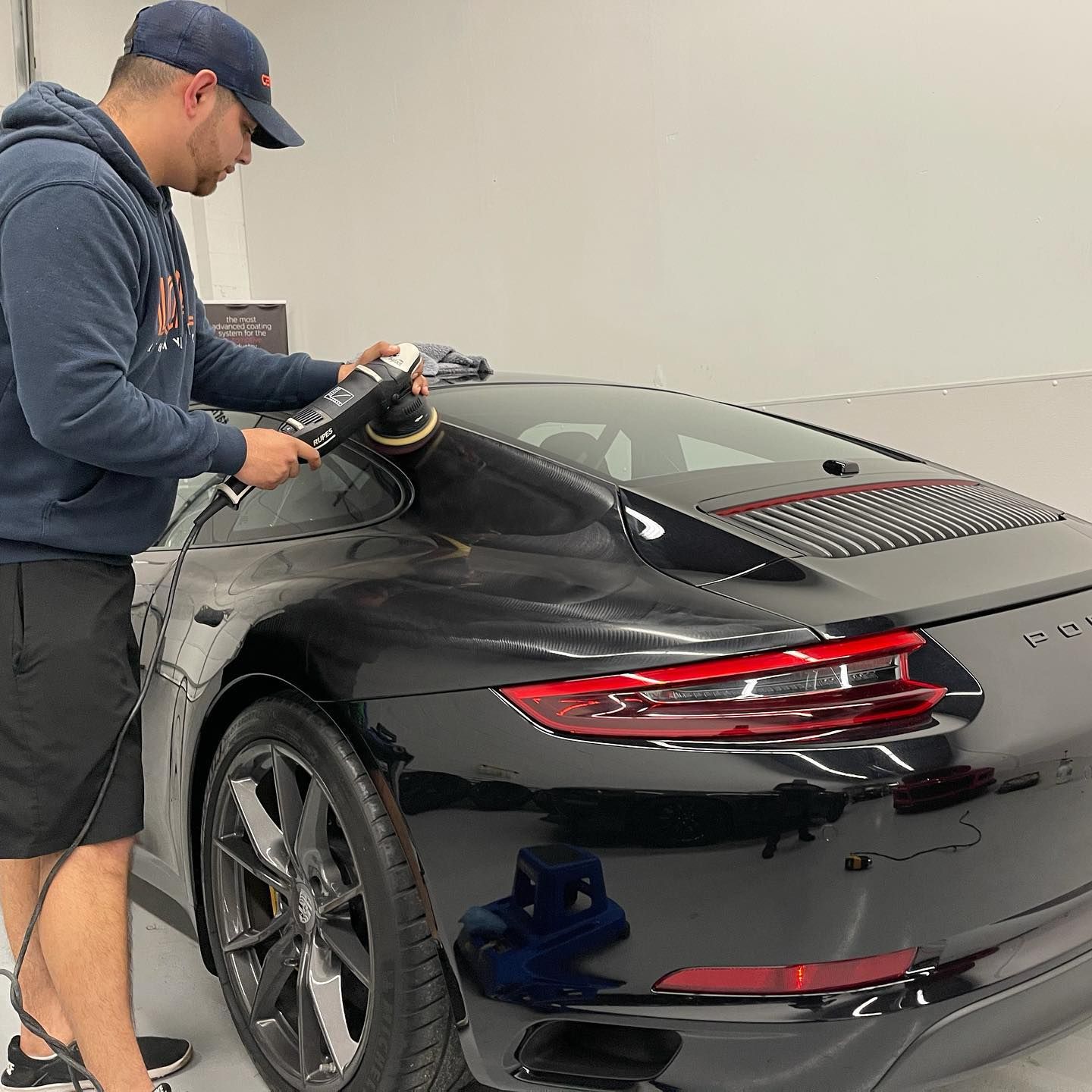 A blue tesla model 3 is parked in a garage.