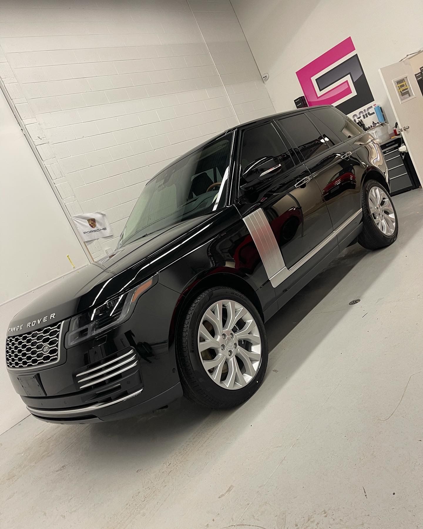A black Range Rover with silver accents and chrome wheels parked inside a brightly lit garage.