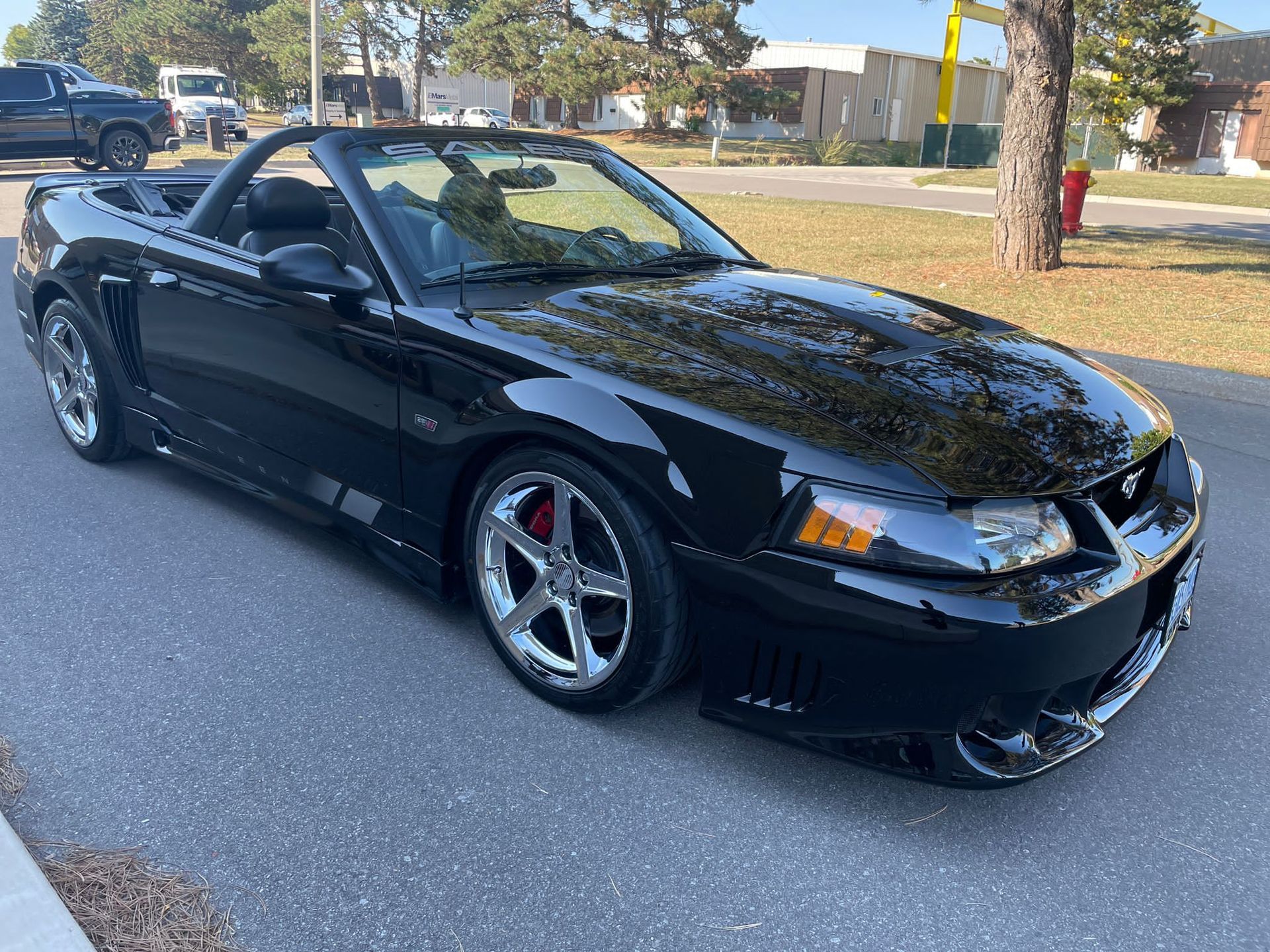 A black Ford Mustang convertible parked on an asphalt surface during the day.