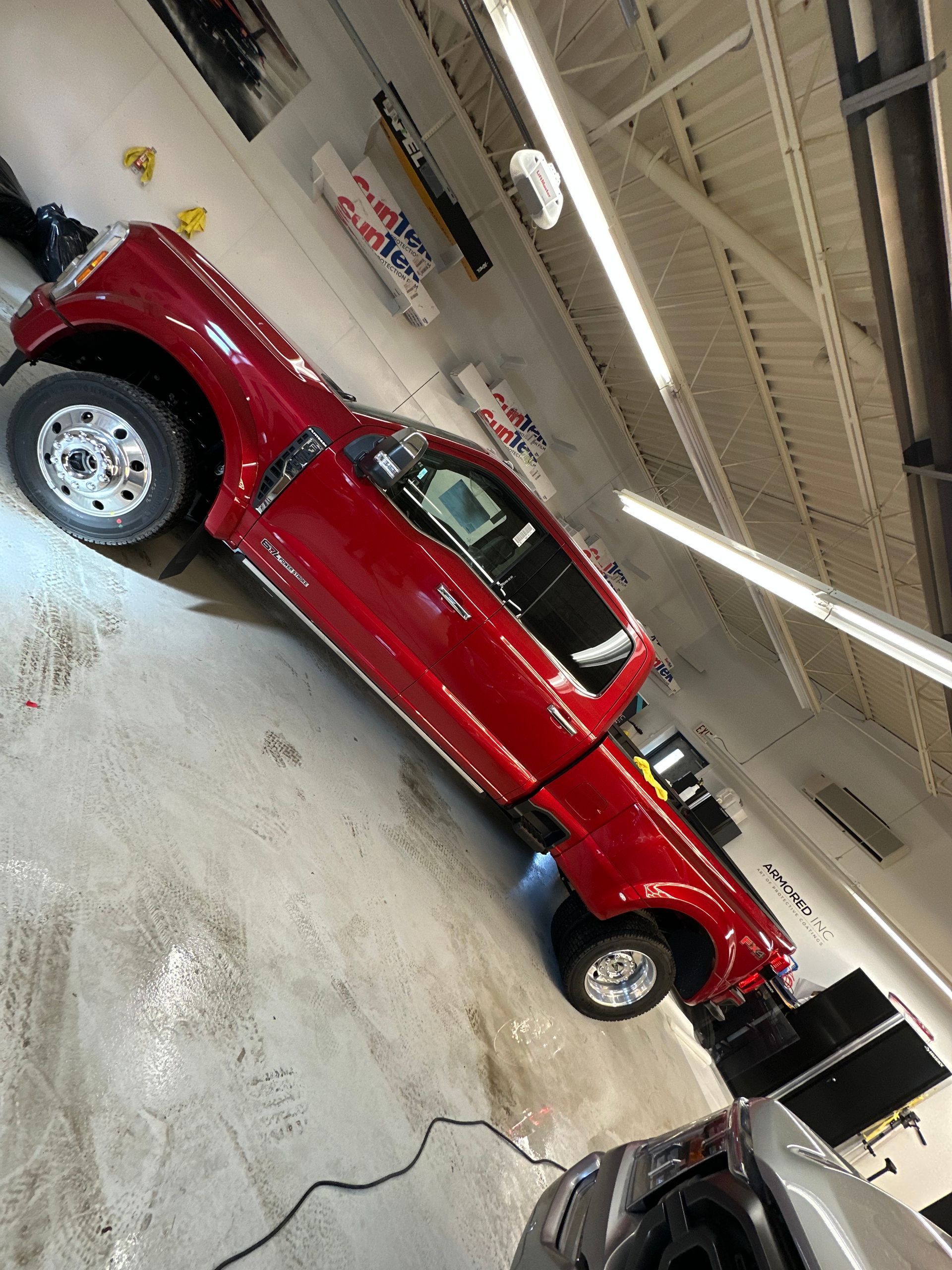 A shiny red pickup truck parked inside a bright, clean automotive service garage.