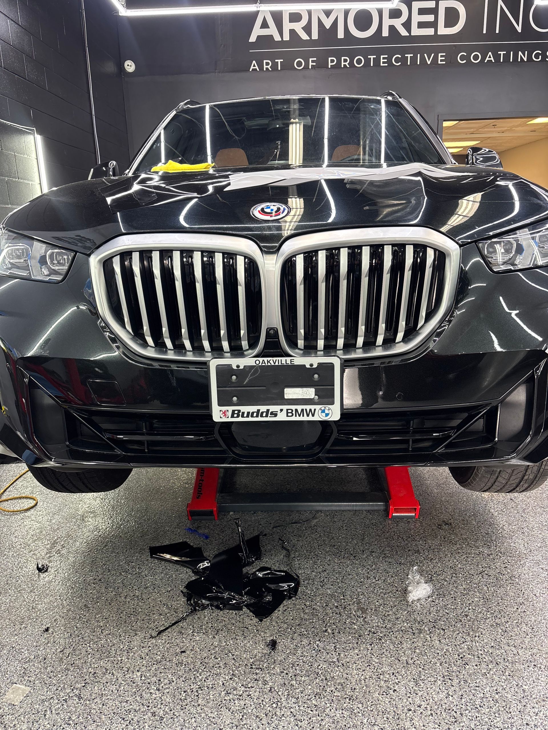 A black BMW SUV parked on a vehicle lift in a garage with a 