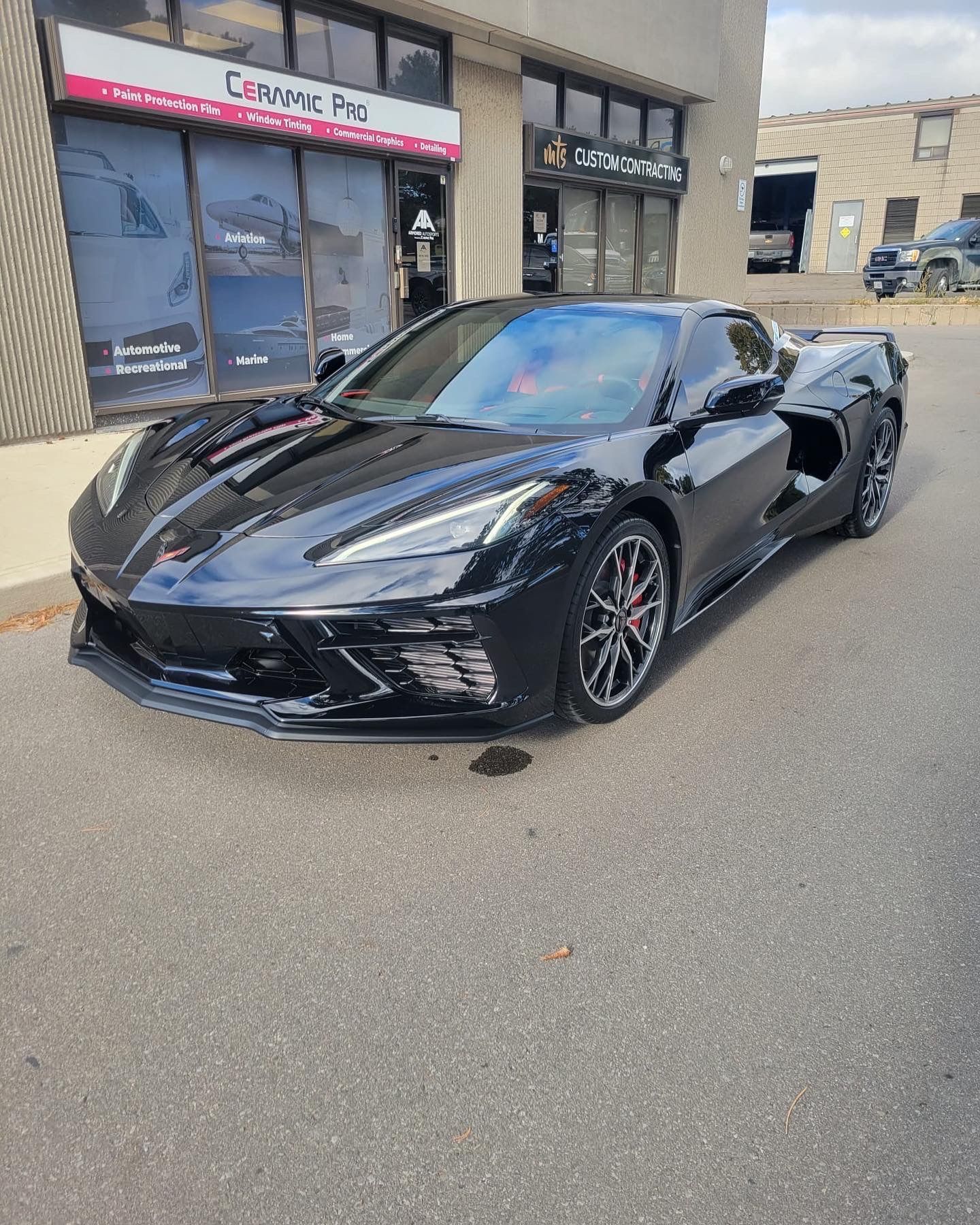 A black Chevrolet Corvette parked in front of a storefront.