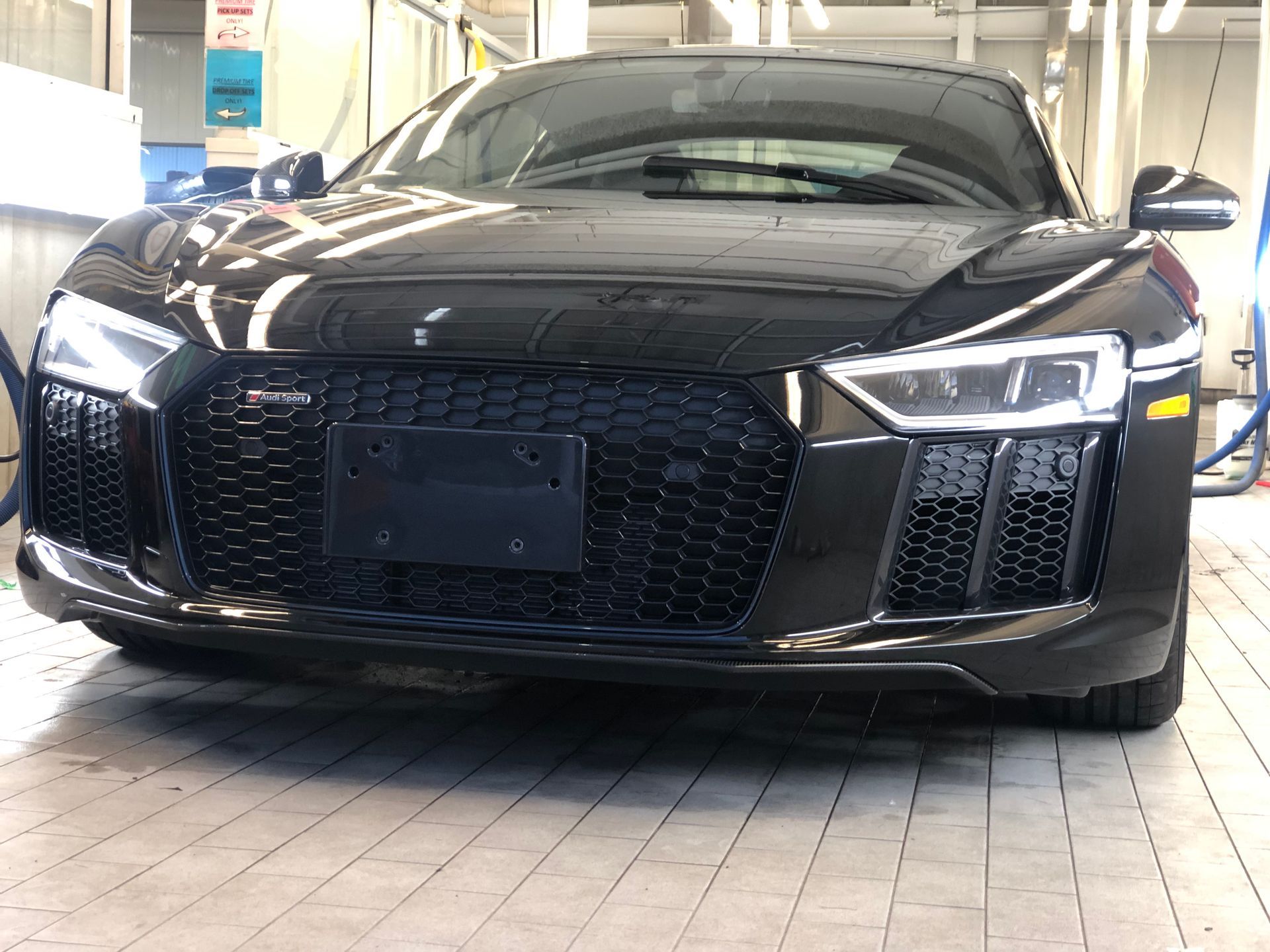 A black Audi R8 sports car parked in an indoor garage or service bay.