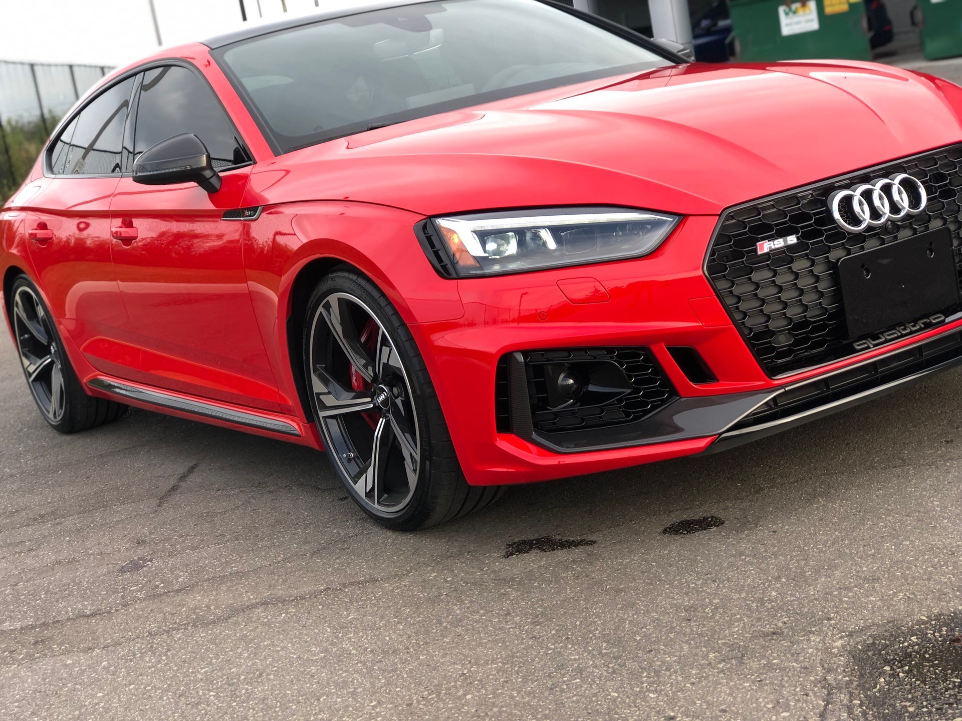 A red Audi RS5 Sportback parked on an asphalt surface.