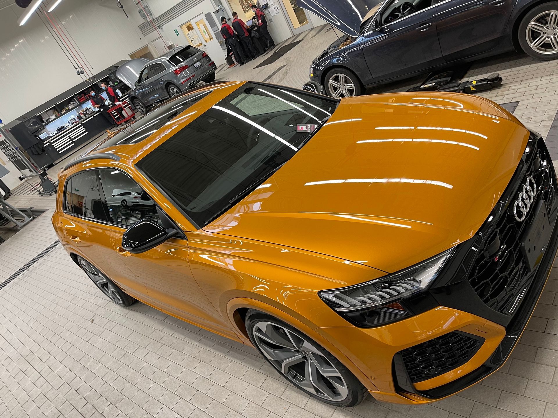A bright yellow Audi RS Q8 parked in a modern, well-lit automotive service center.