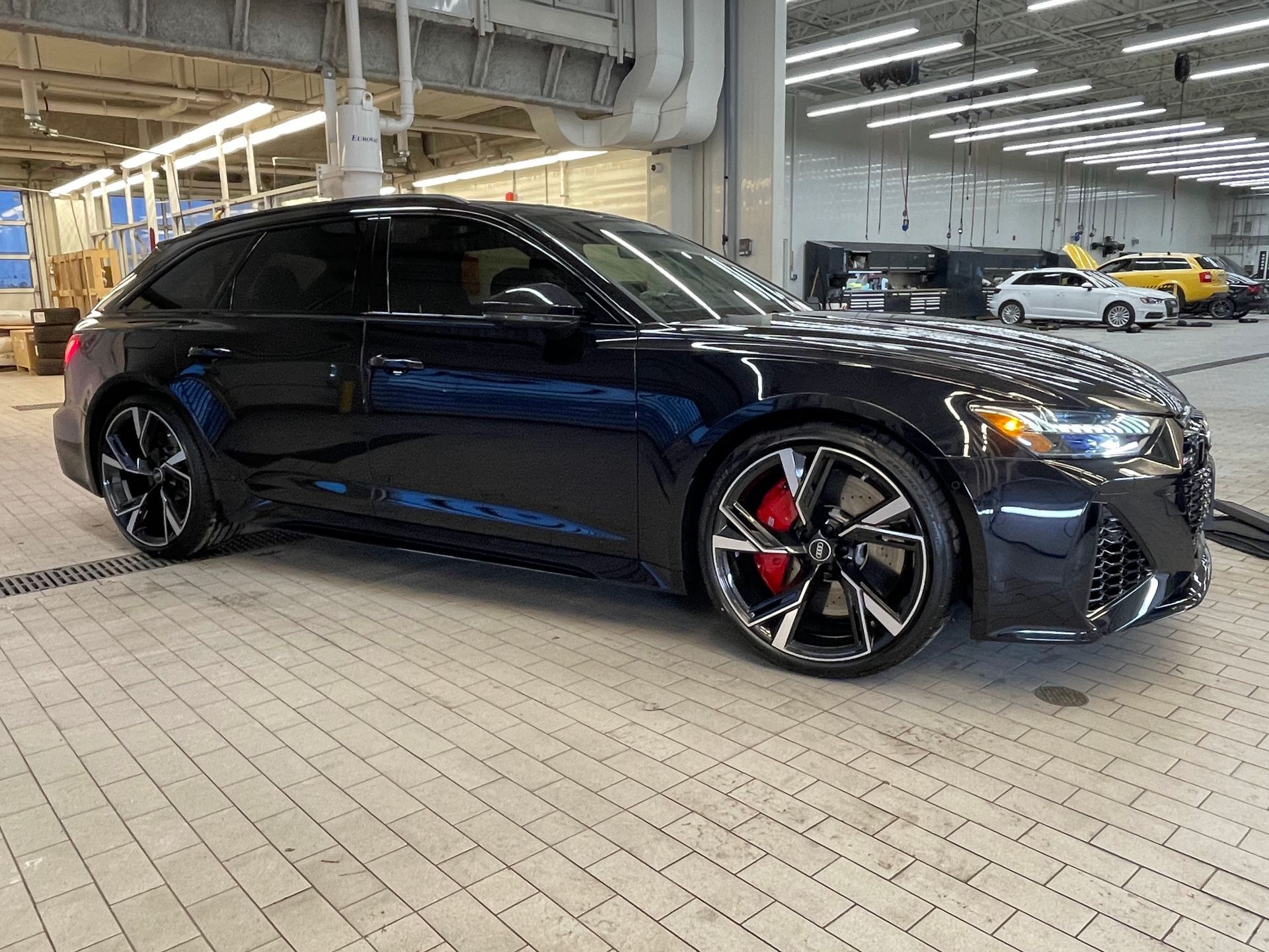 A black Audi station wagon parked on a tiled floor inside a well-lit service center.