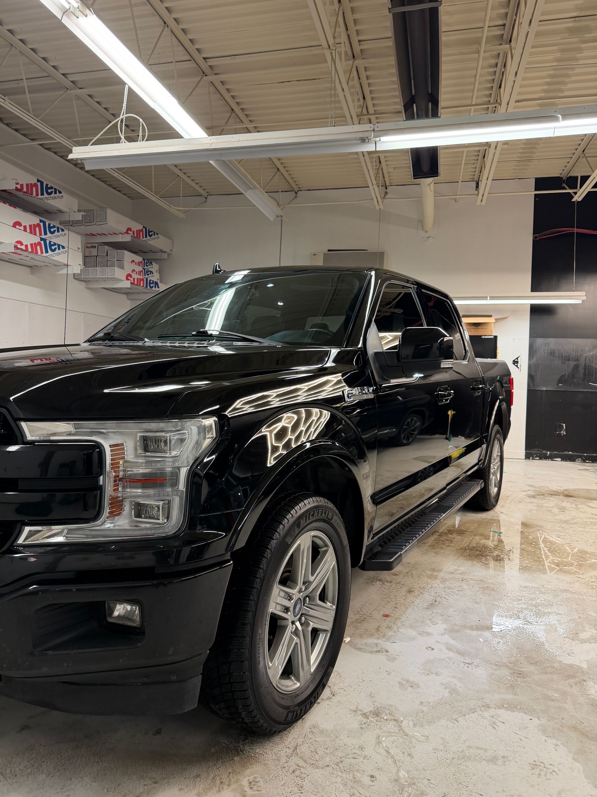A black Ford F-150 pickup truck parked inside a bright, industrial-style garage.