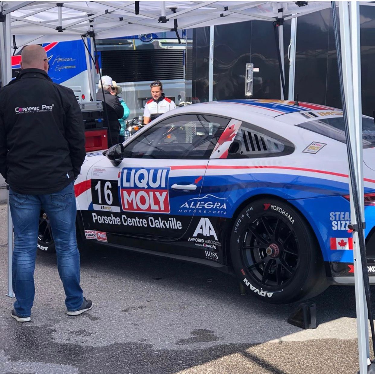 A race car with Liqui Moly branding parked under a white canopy with crew members standing nearby.