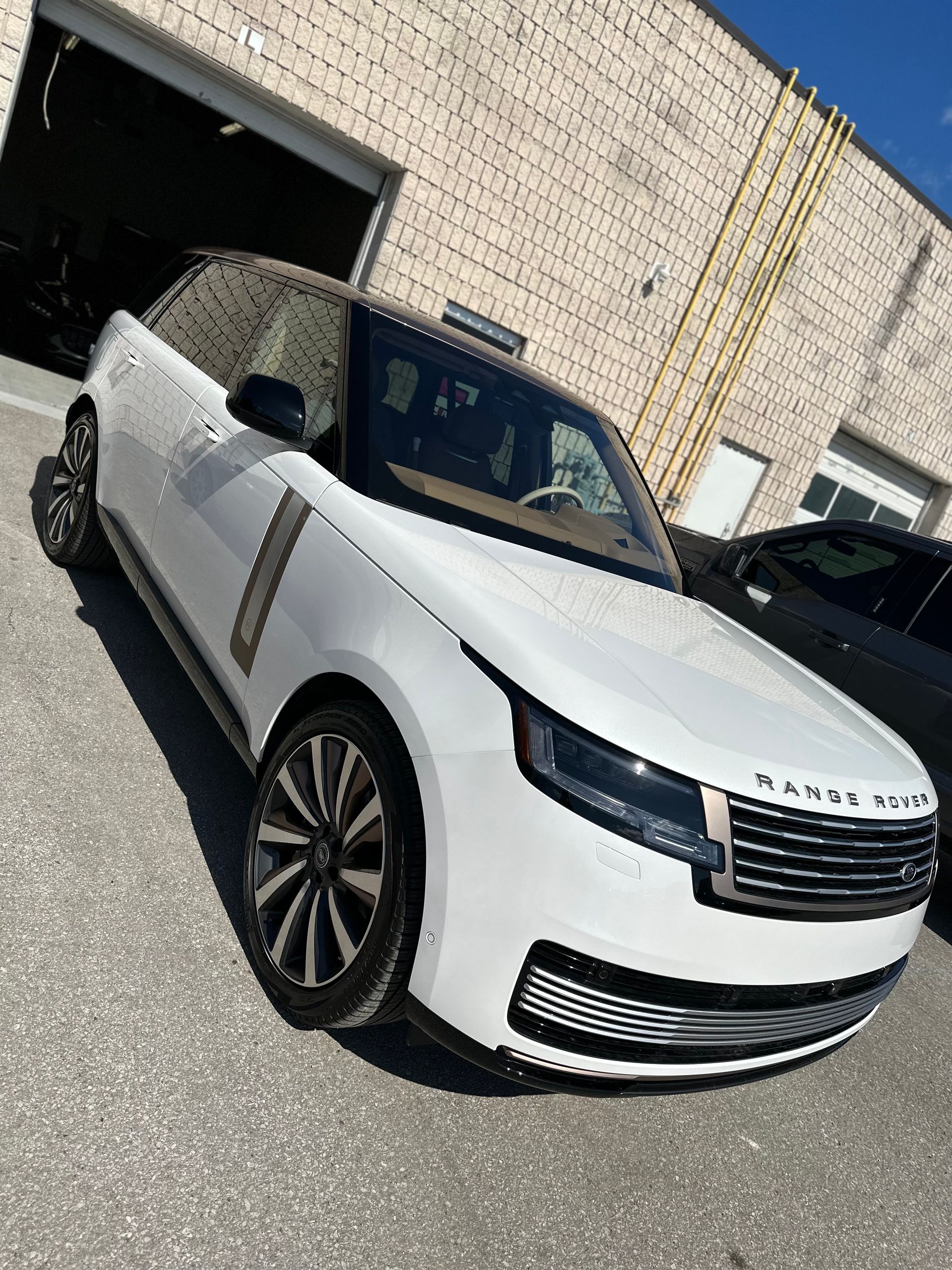 A white Land Rover Range Rover parked outdoors near a building with brick walls.