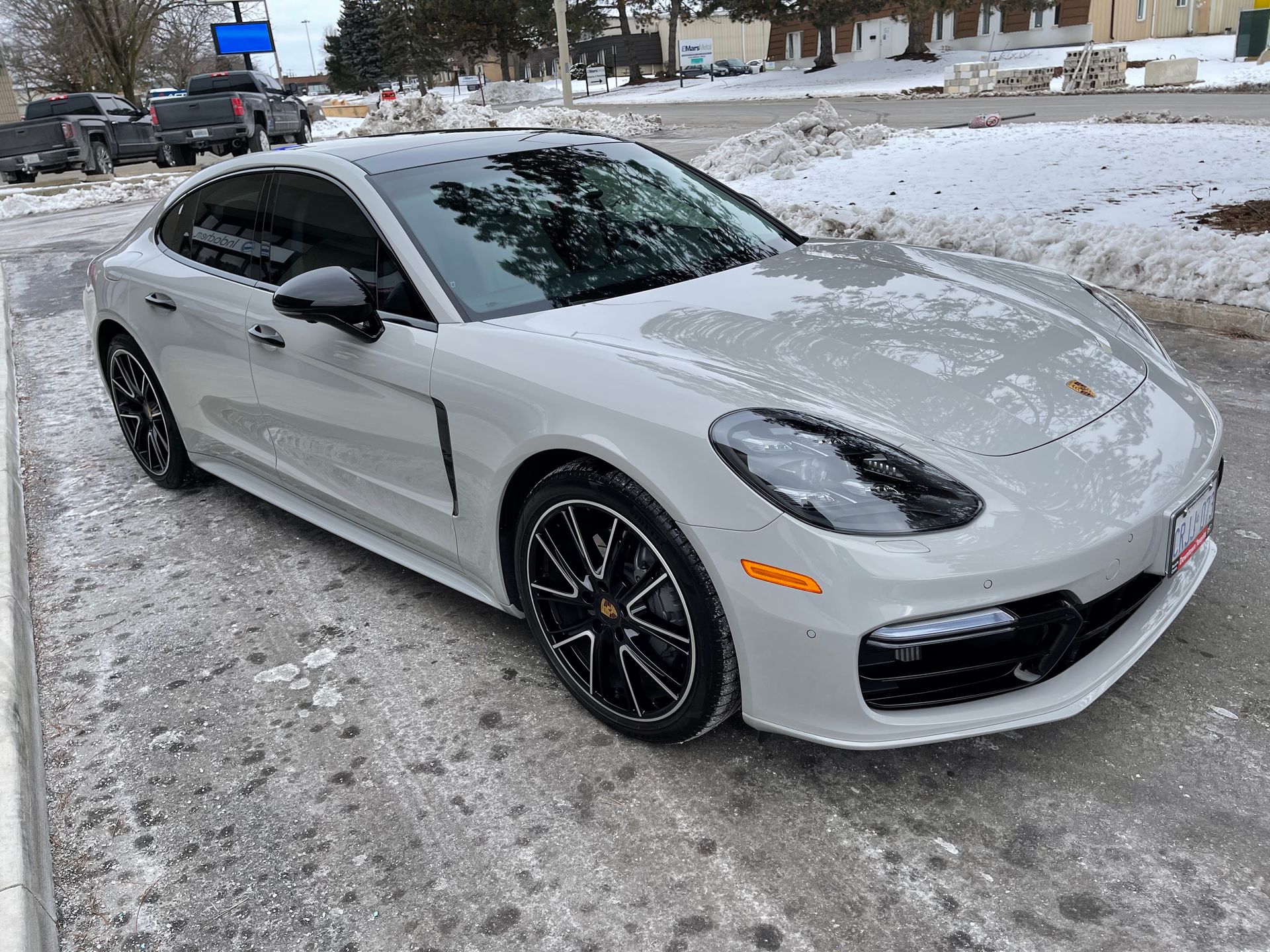 A light gray Porsche Panamera parked on a snowy, paved surface.