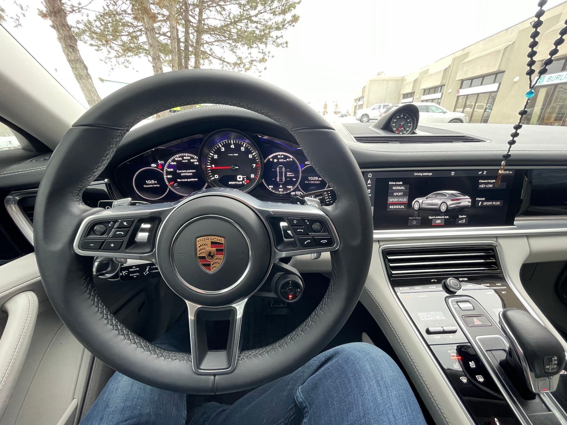 Interior view from the driver's seat of a Porsche showing the steering wheel, dashboard, and digital displays.