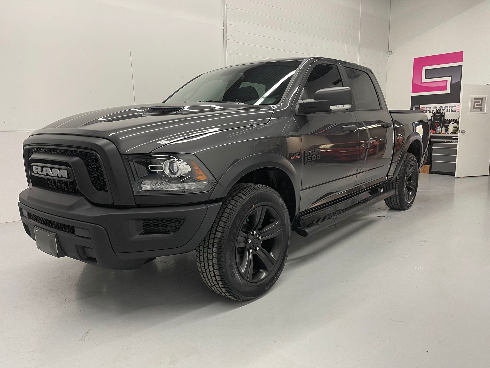 A dark gray Ram pickup truck parked in a well-lit indoor automotive shop.