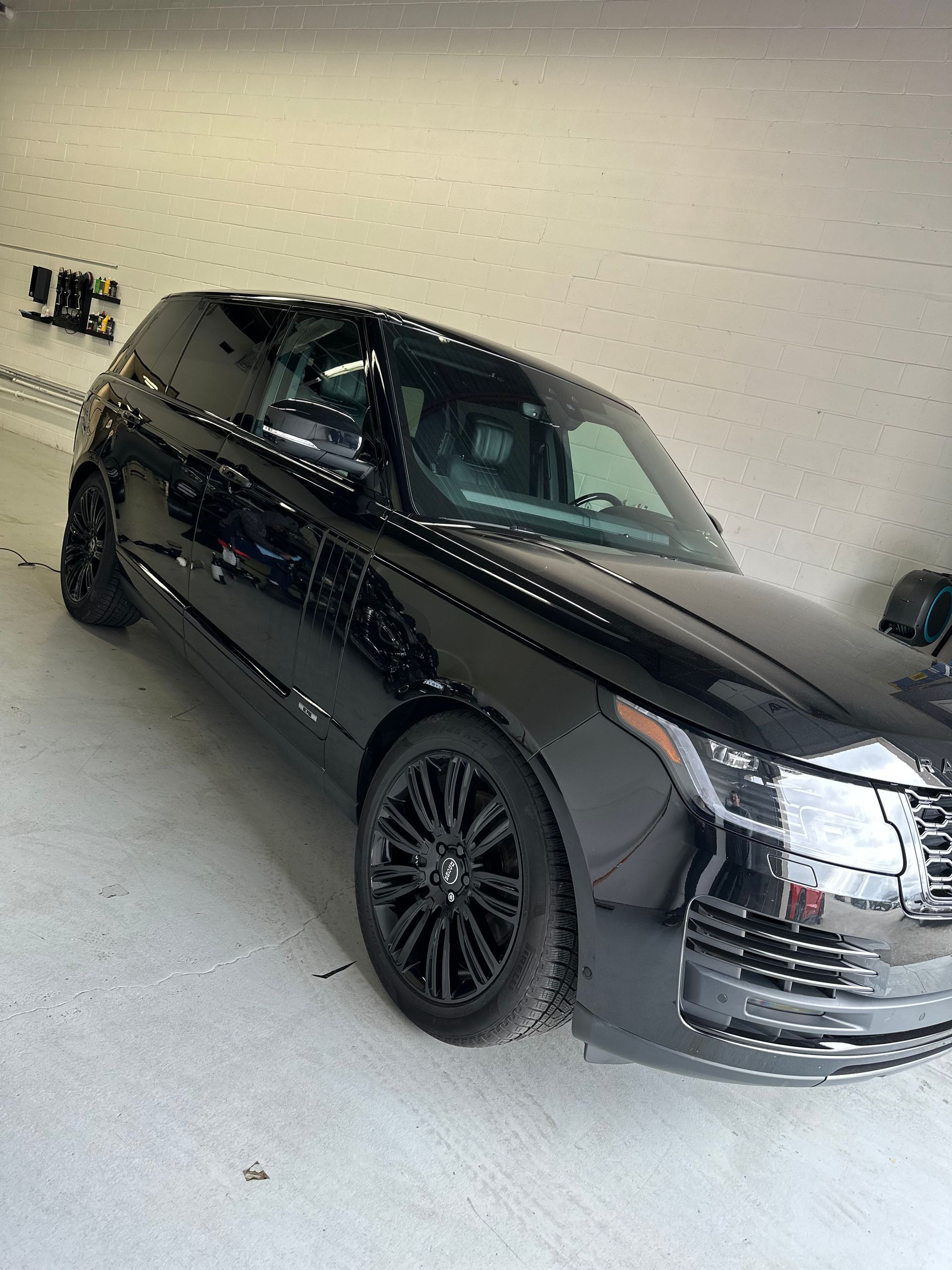 A black Range Rover parked in a bright, white-walled indoor garage or studio.