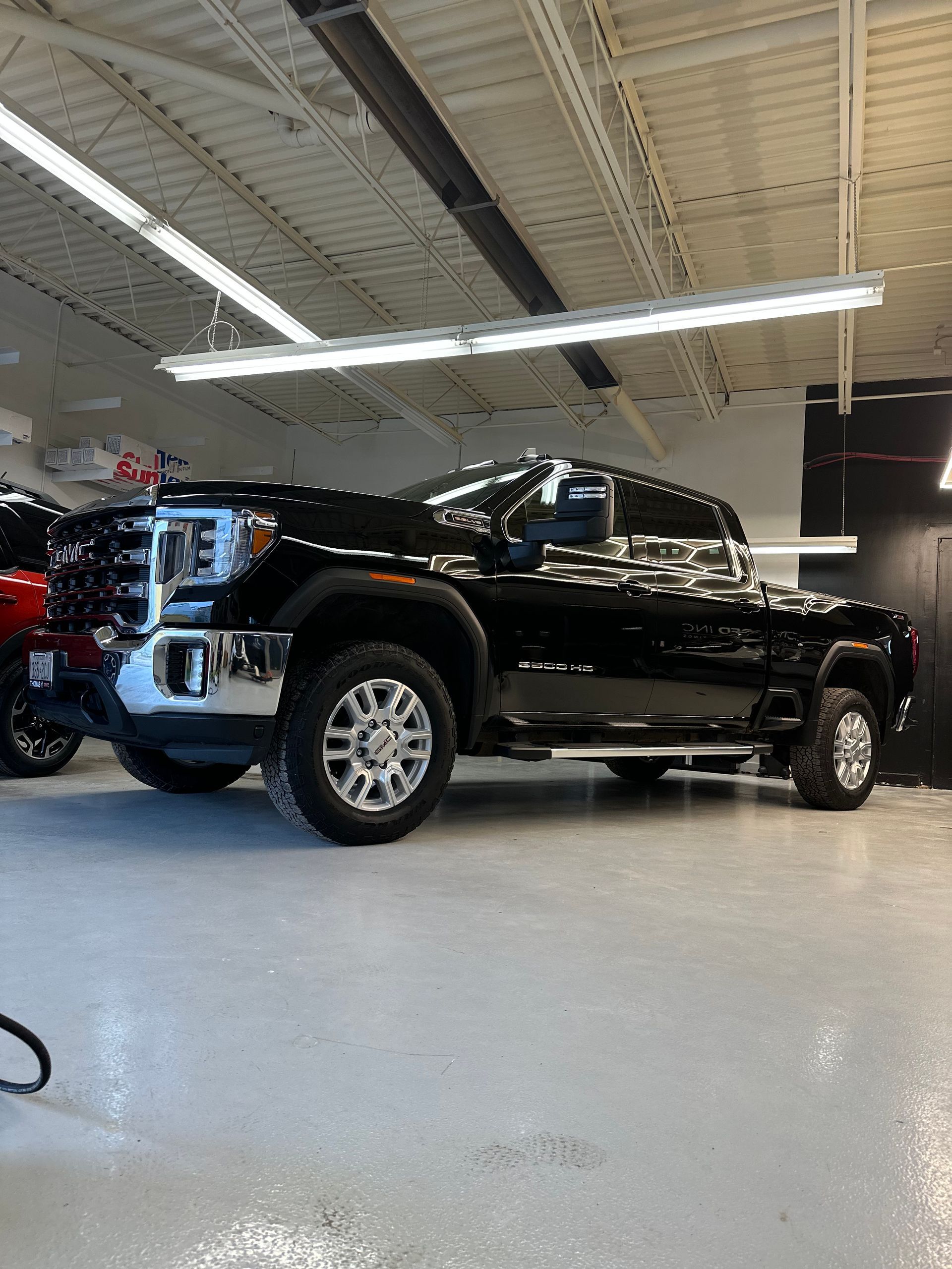 A black GMC Sierra pickup truck parked on a polished concrete floor inside a brightly lit garage.