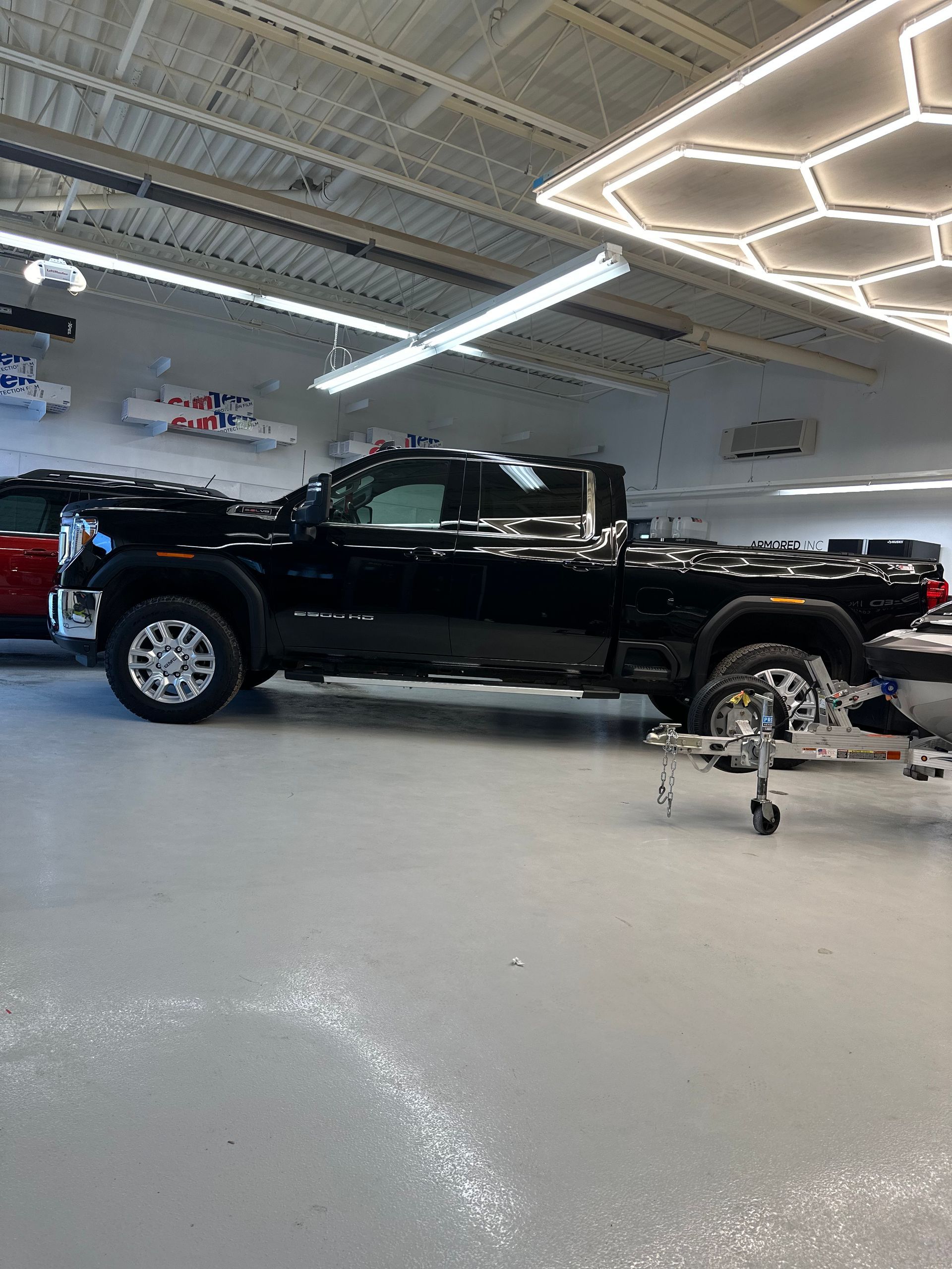 A black pickup truck parked inside a bright, well-lit garage with a modern hexagonal ceiling light fixture.
