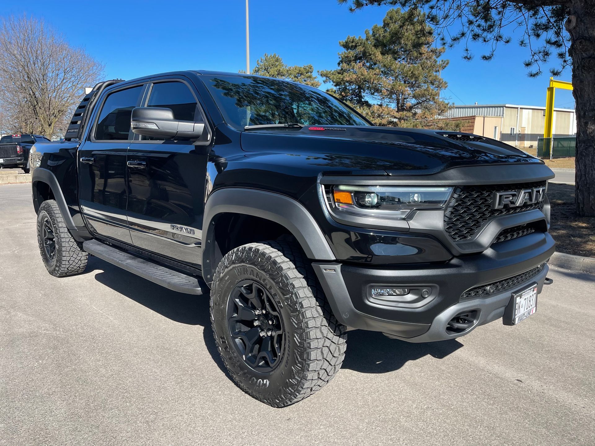A black Ram TRX pickup truck parked on an asphalt lot on a sunny day.