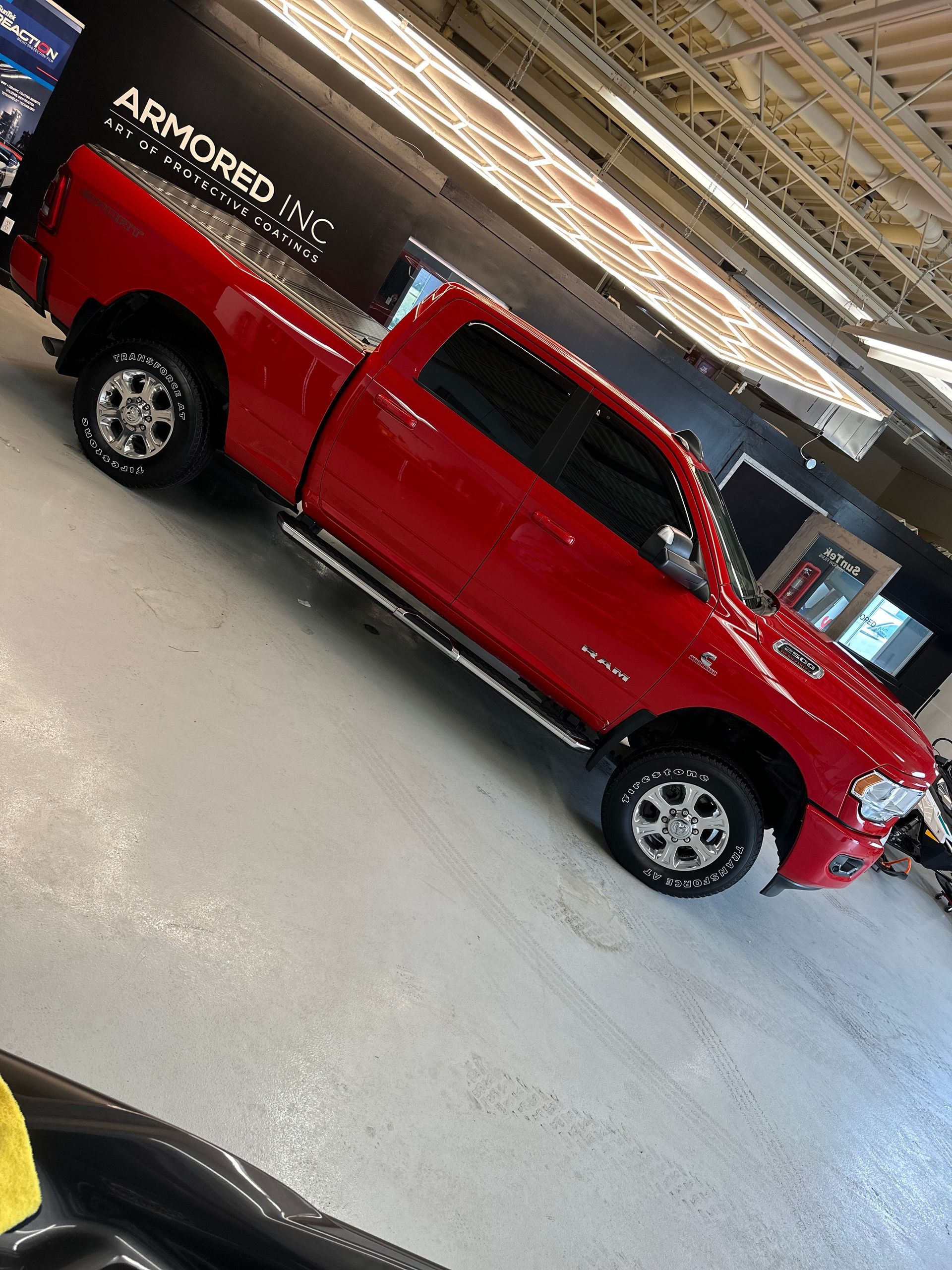 A bright red Ram pickup truck parked inside a bright, industrial-style garage.
