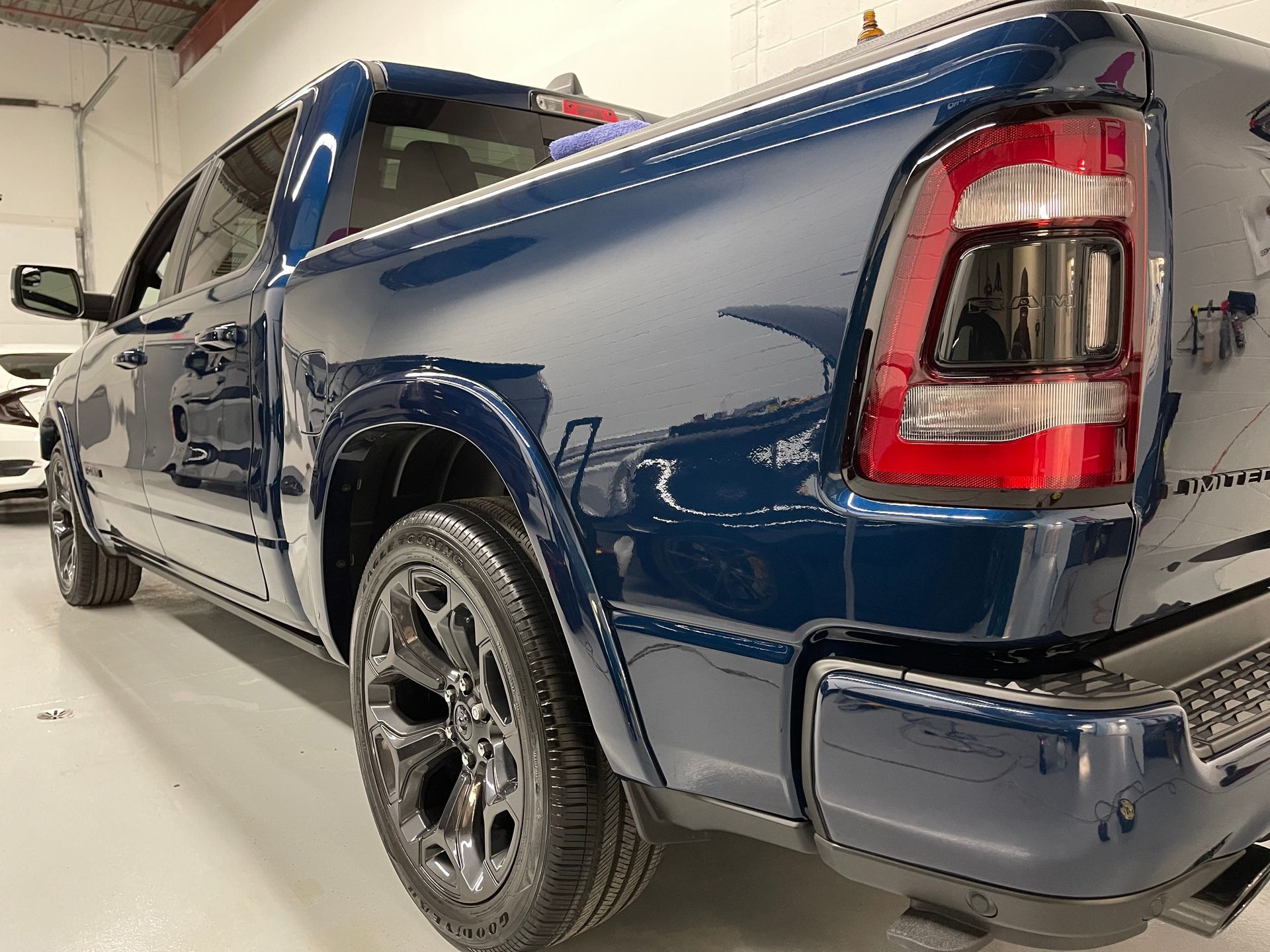 Dark blue Ram pickup truck parked in a well-lit garage, shown from the rear three-quarter view.