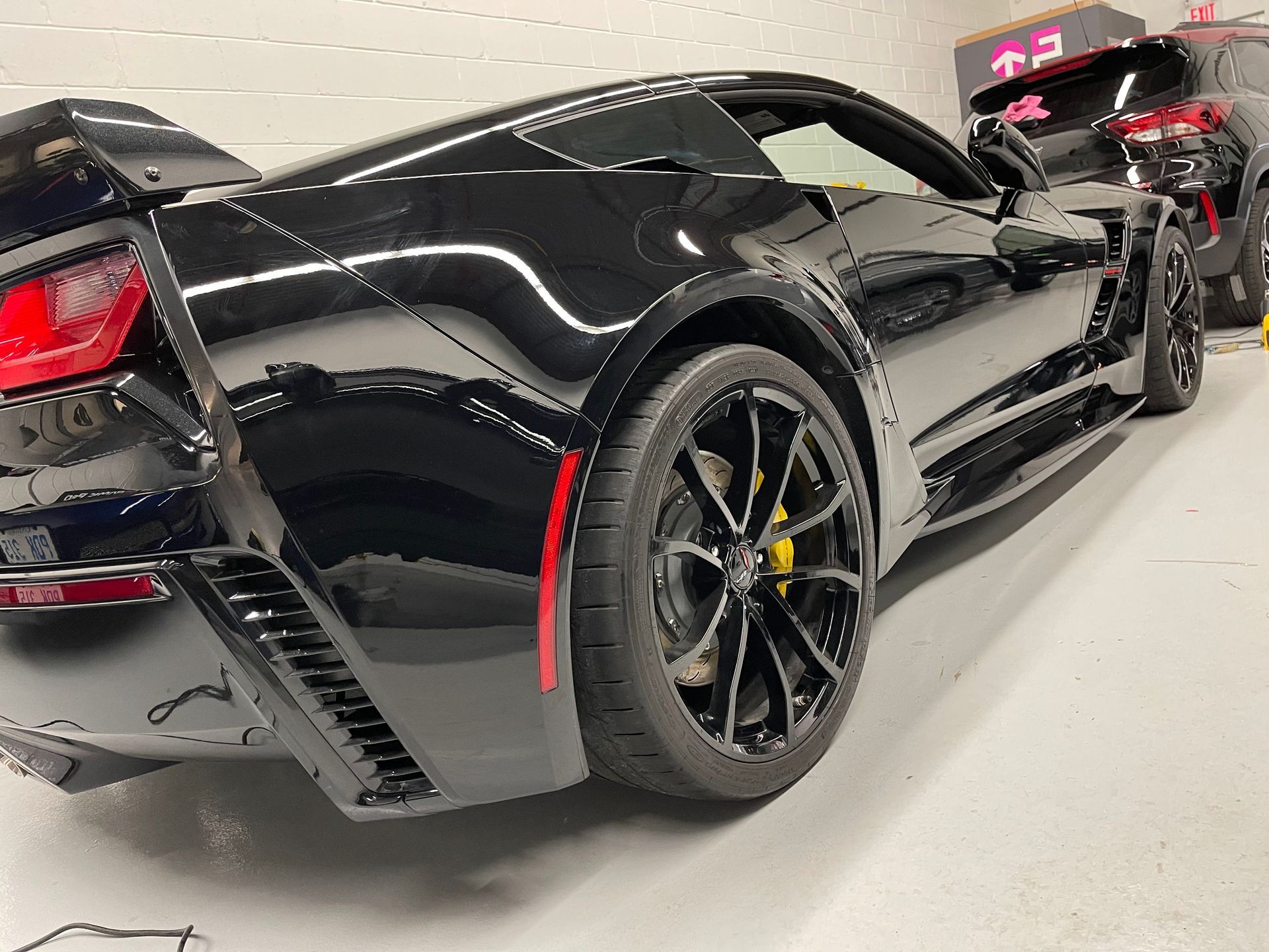 A black Chevrolet Corvette Z06 with yellow brake calipers parked in a garage.