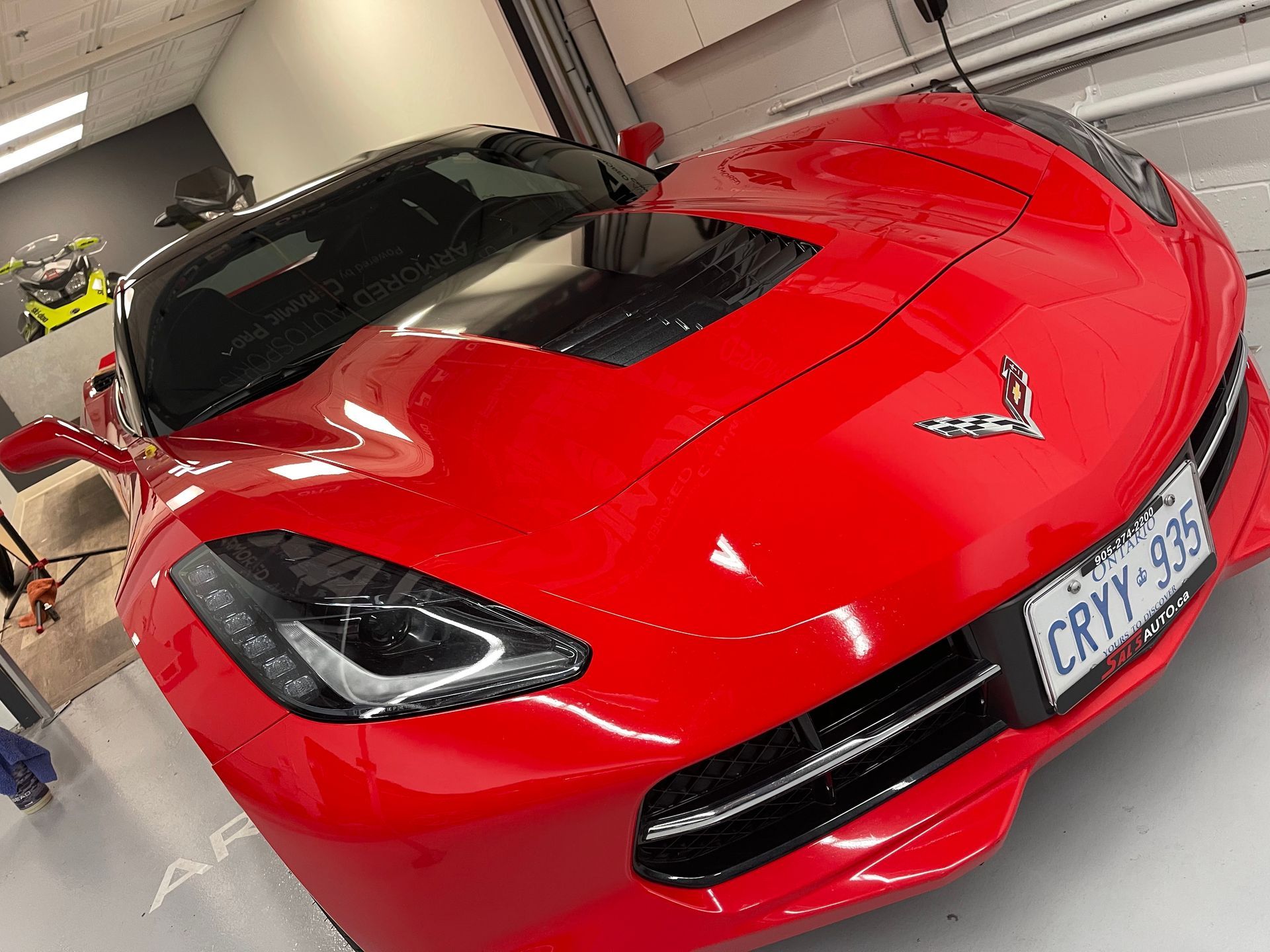 A bright red Chevrolet Corvette sports car parked indoors on a white garage floor.