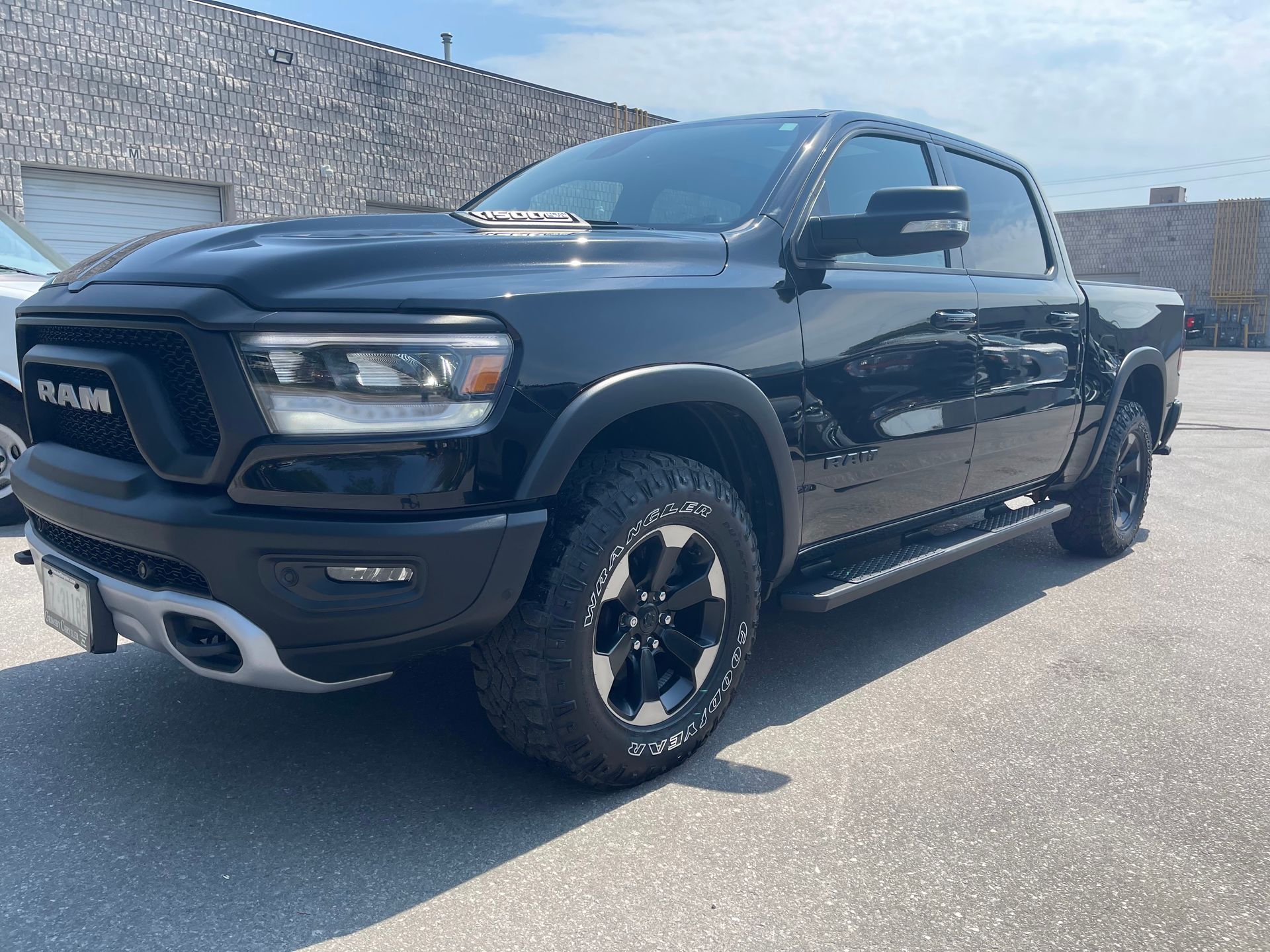A black Ram 1500 Rebel pickup truck parked on a paved lot on a sunny day.