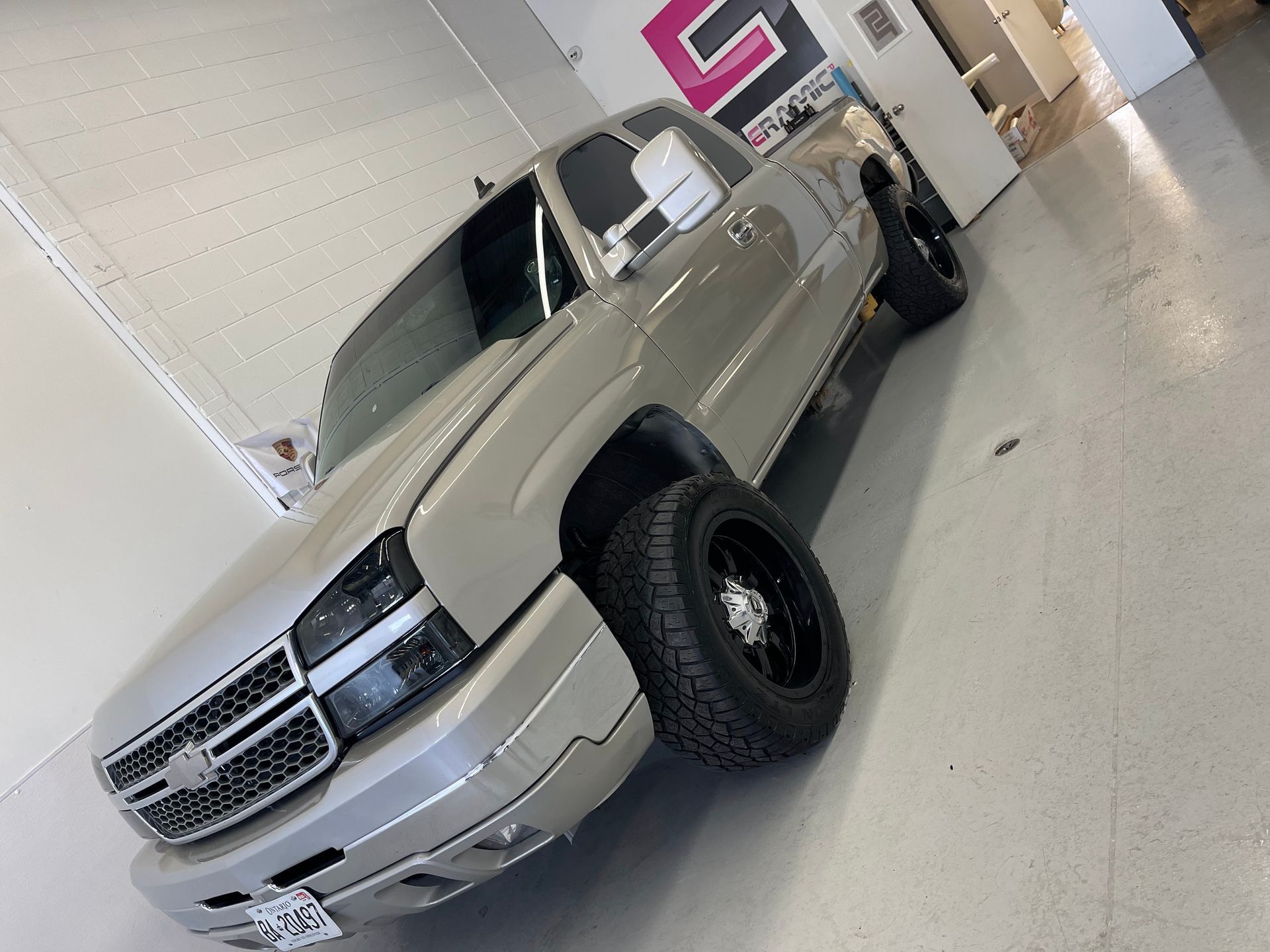 A tan Chevrolet Silverado pickup truck parked at an angle inside a garage with white walls and a light-colored floor.