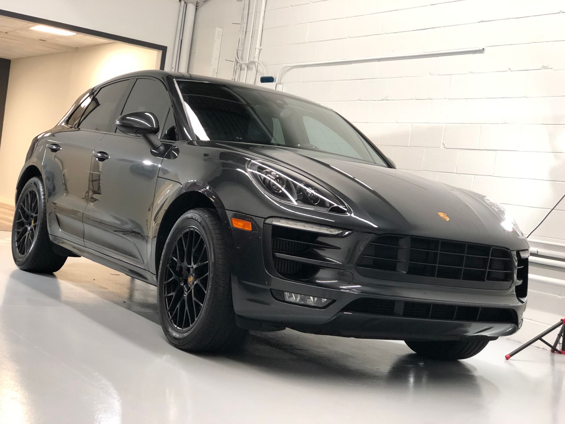 A black Porsche Macan parked in a bright, modern garage.