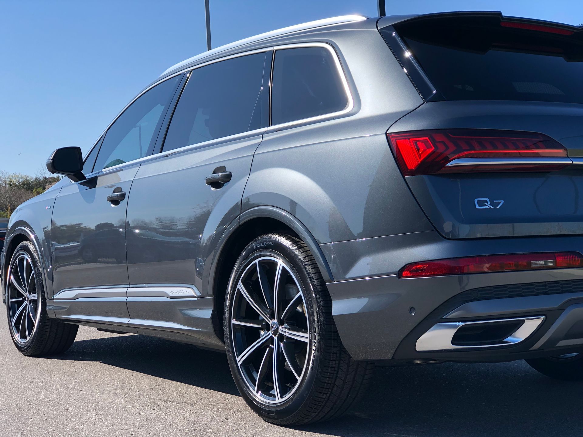 A gray Audi Q7 SUV parked on pavement, angled to show its rear and passenger side.