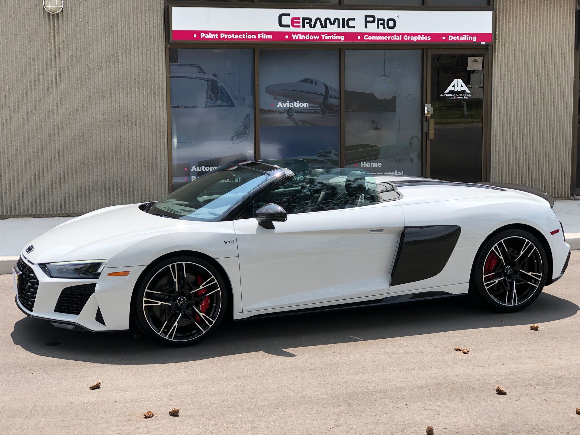 A white Audi R8 convertible parked outside a Ceramic Pro shop.