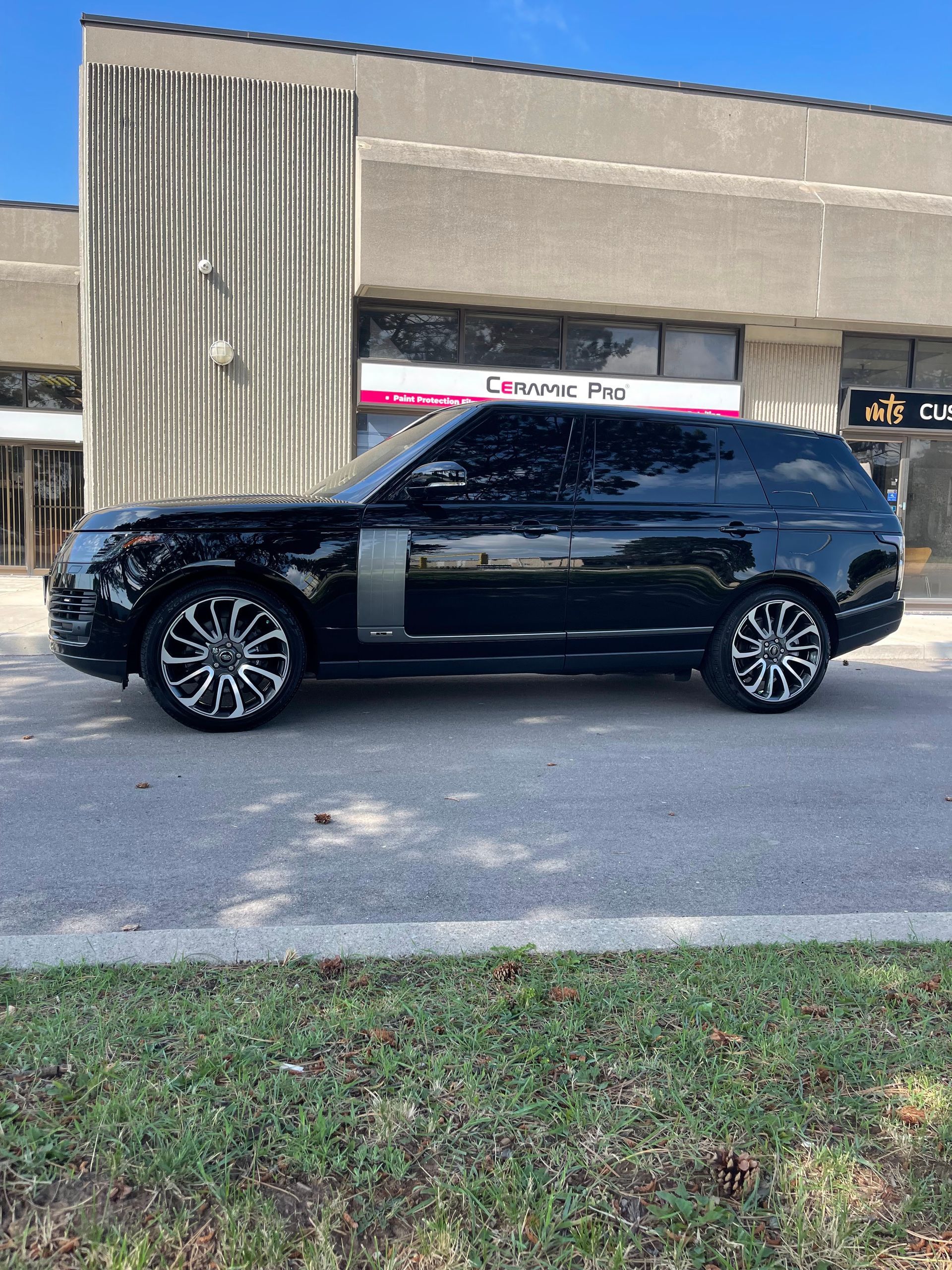A black Land Rover Range Rover parked in front of a commercial building on a sunny day.