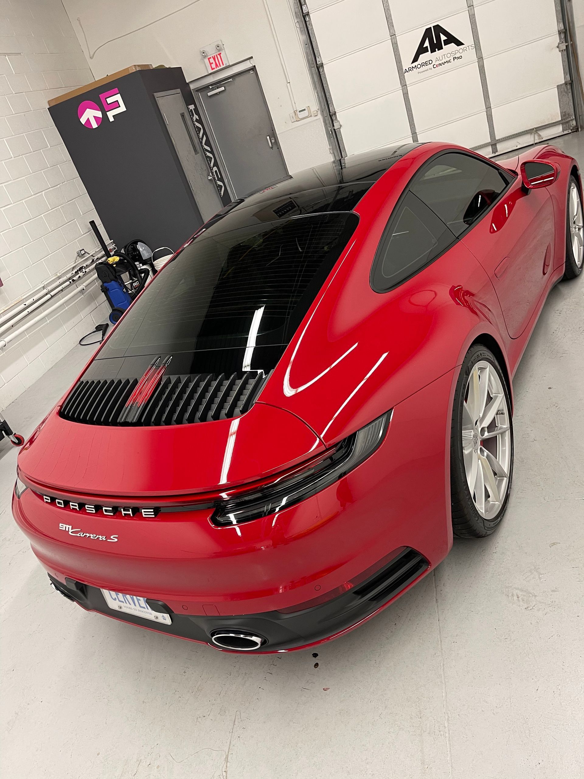 Red Porsche 911 parked inside a garage, viewed from the rear angle.