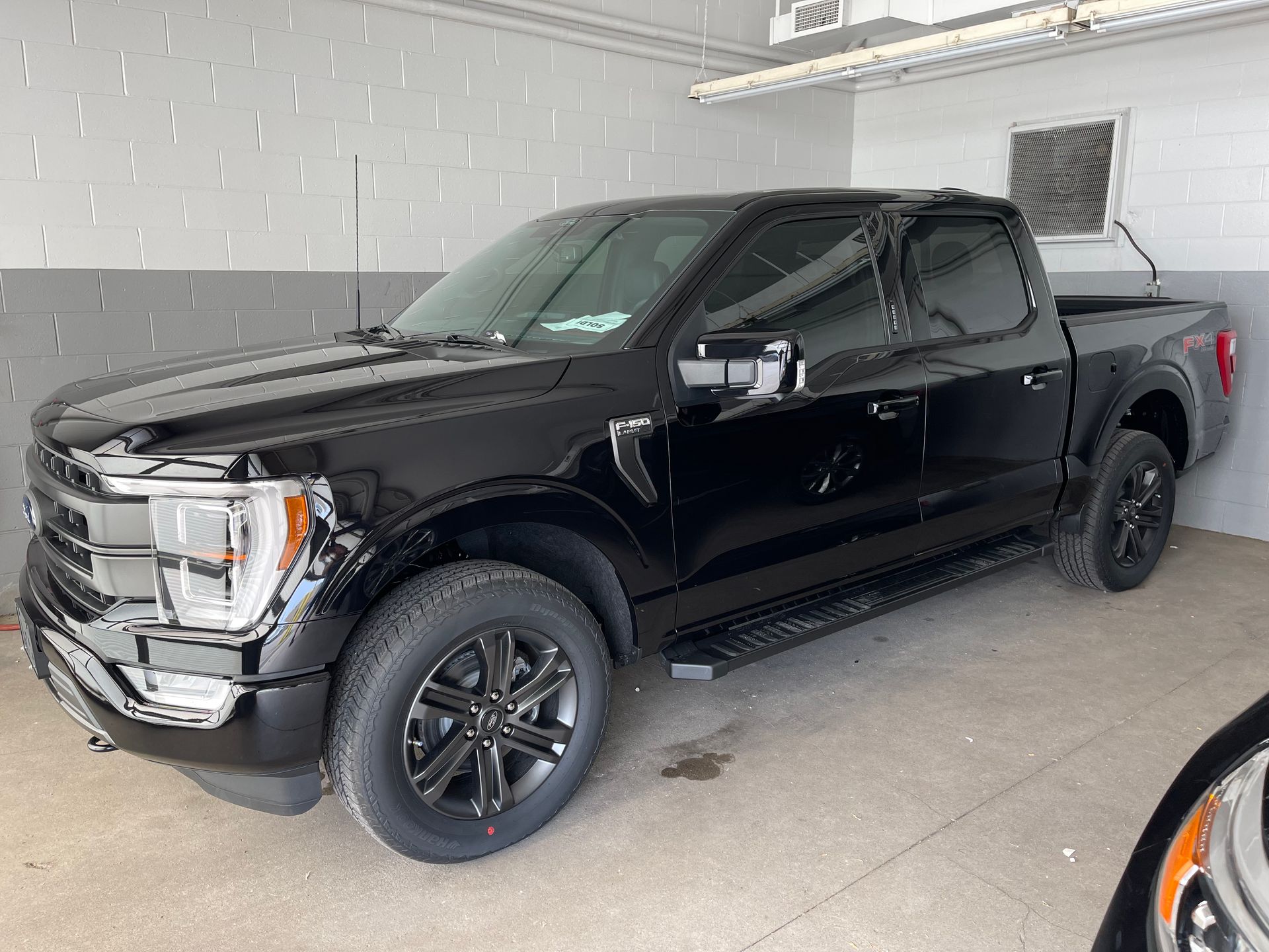 A black Ford F-150 pickup truck parked inside a bright, clean garage.