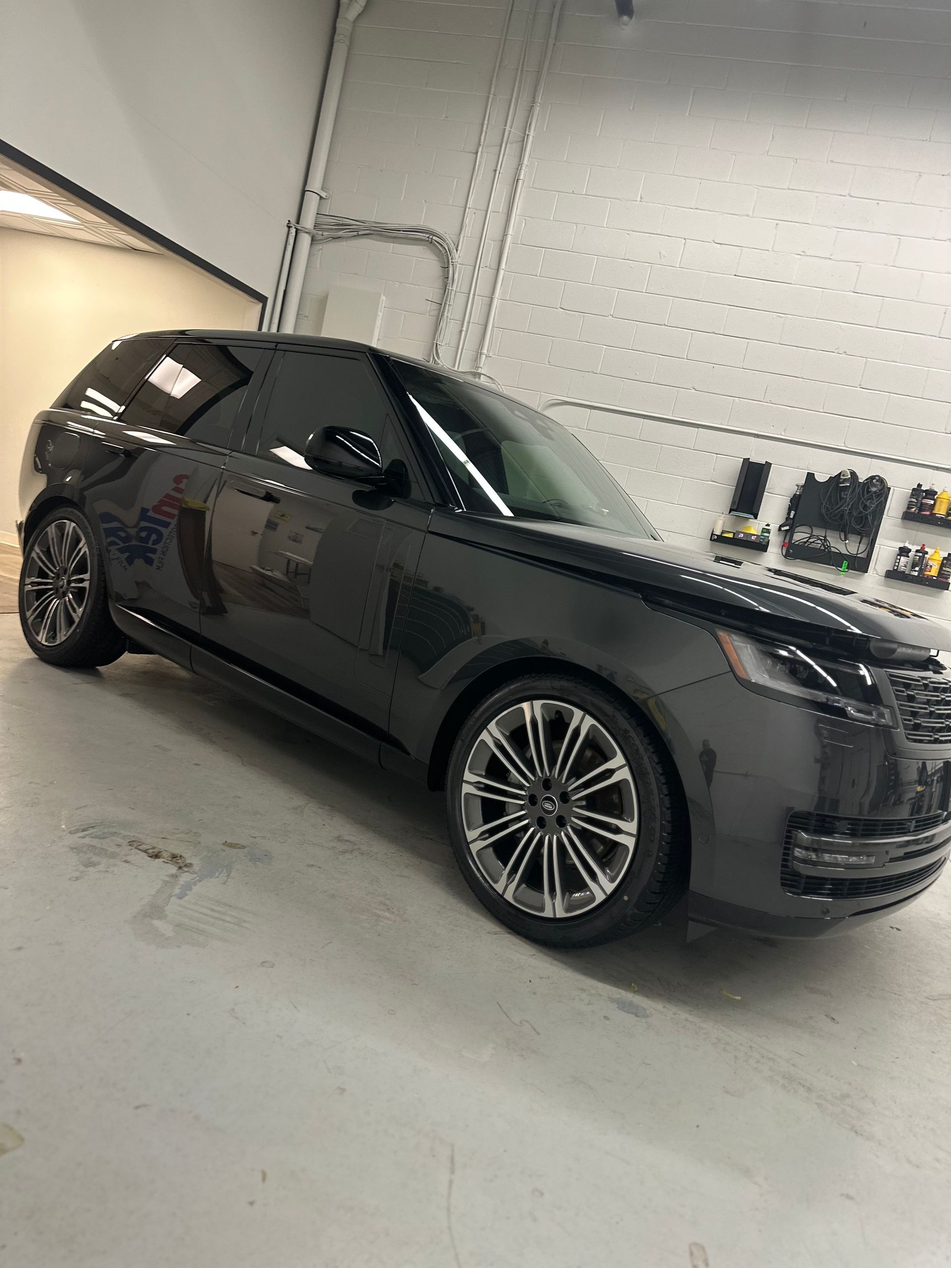 A black Range Rover parked indoors on a concrete floor in a workshop setting.