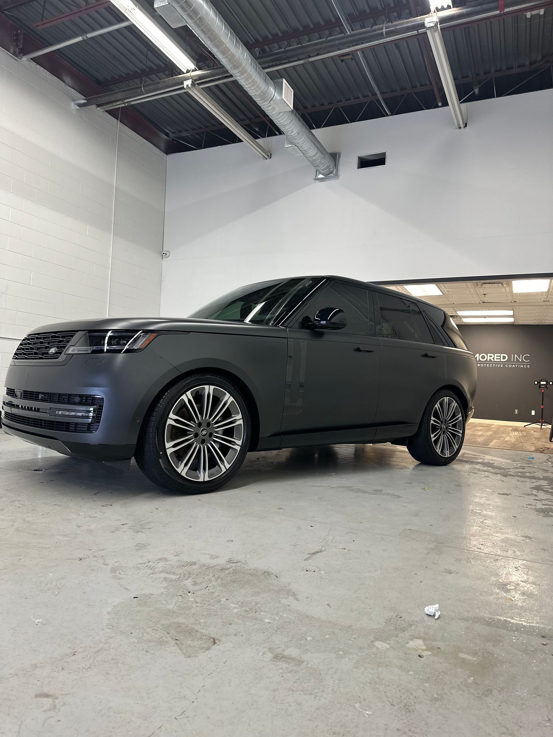 Matte black Range Rover parked inside a garage with bright overhead lighting.