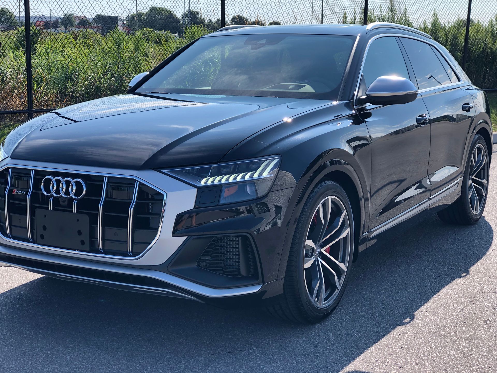Black Audi Q8 SUV parked on a paved lot on a sunny day.