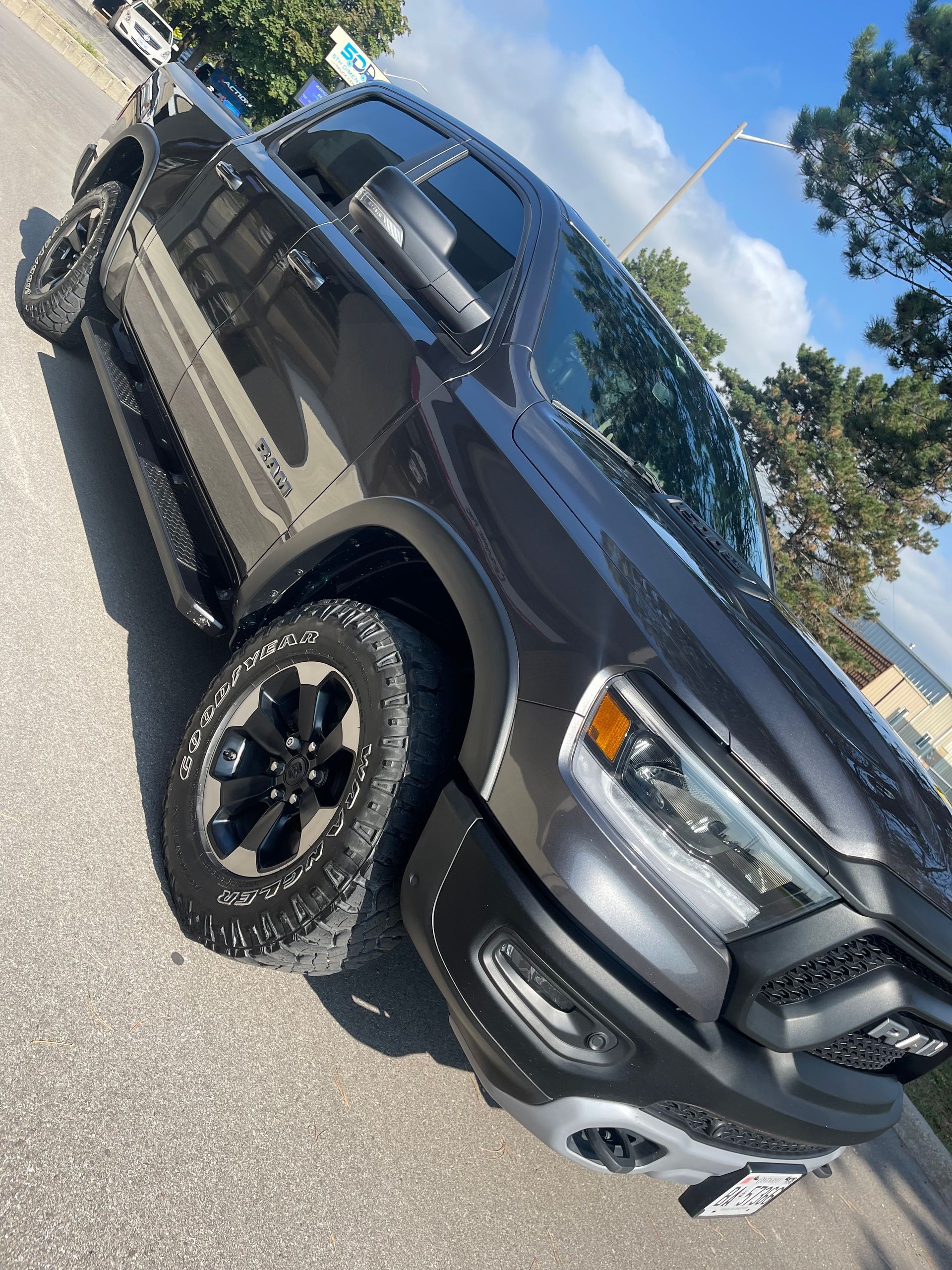 A dark gray Ram 1500 Rebel pickup truck parked at an angle on an asphalt surface under a sunny sky.