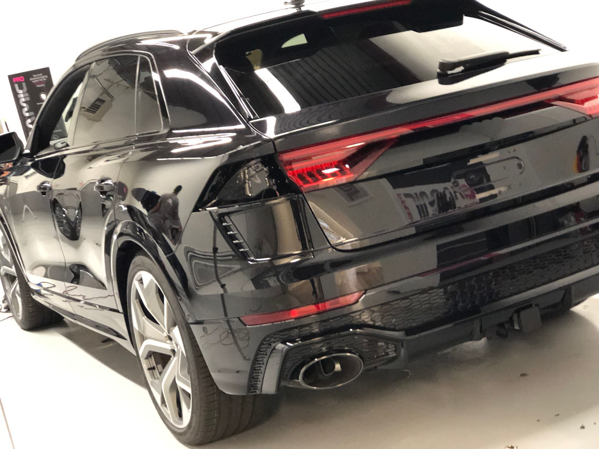 A sleek, black Audi SUV shown from the rear three-quarter angle in a brightly lit garage.