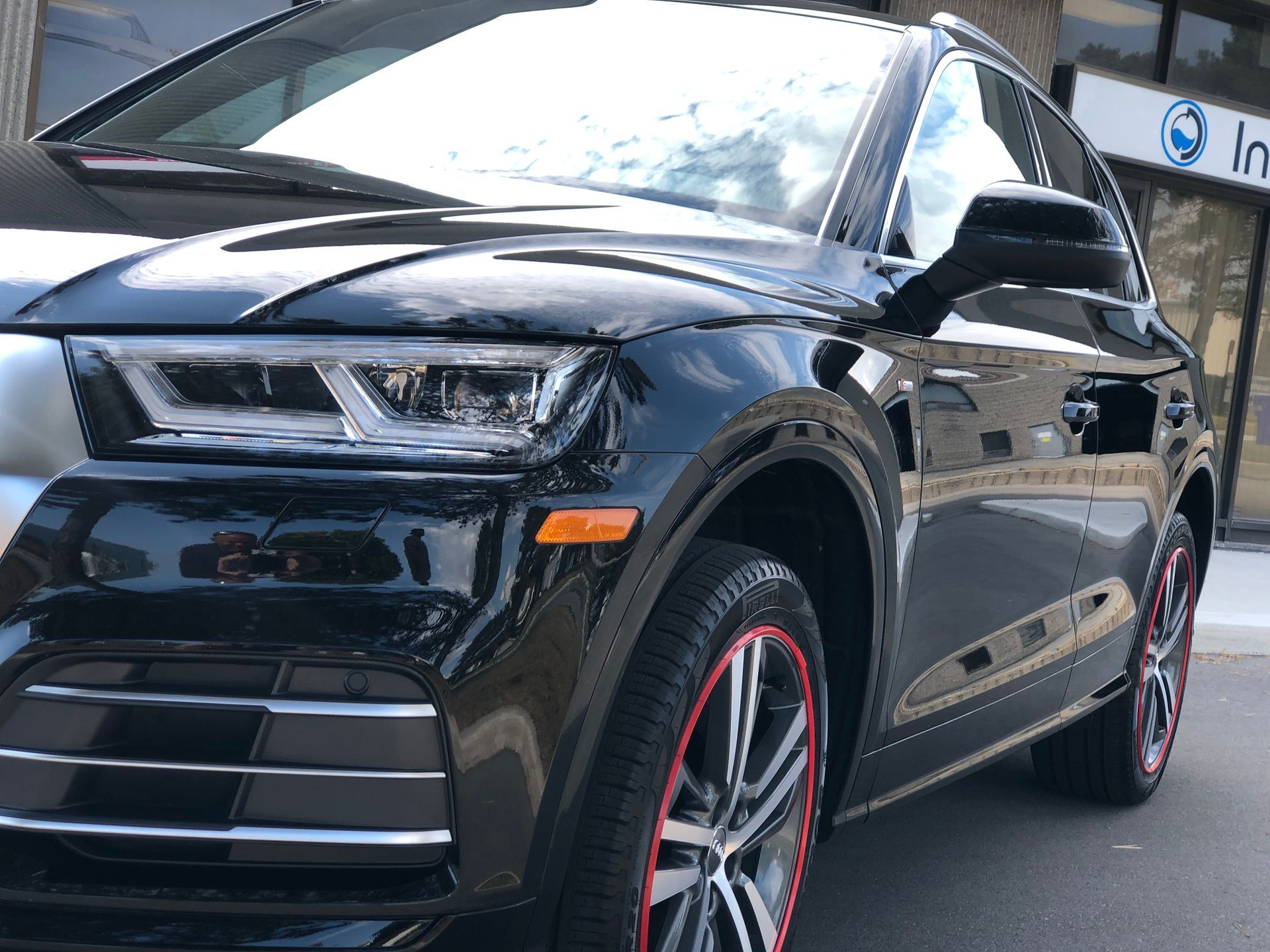 A black Audi SUV parked outdoors, featuring custom rims with red accents on the tires.