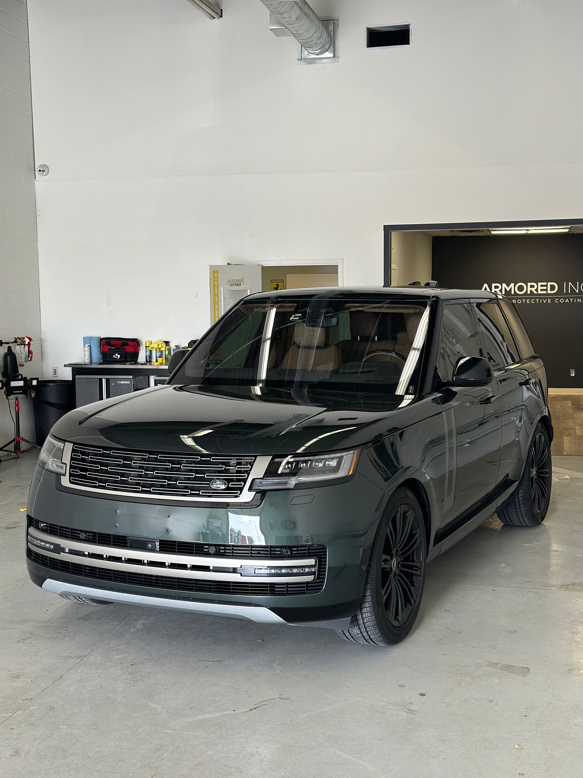 A dark green Range Rover parked inside a brightly lit, industrial-style garage.